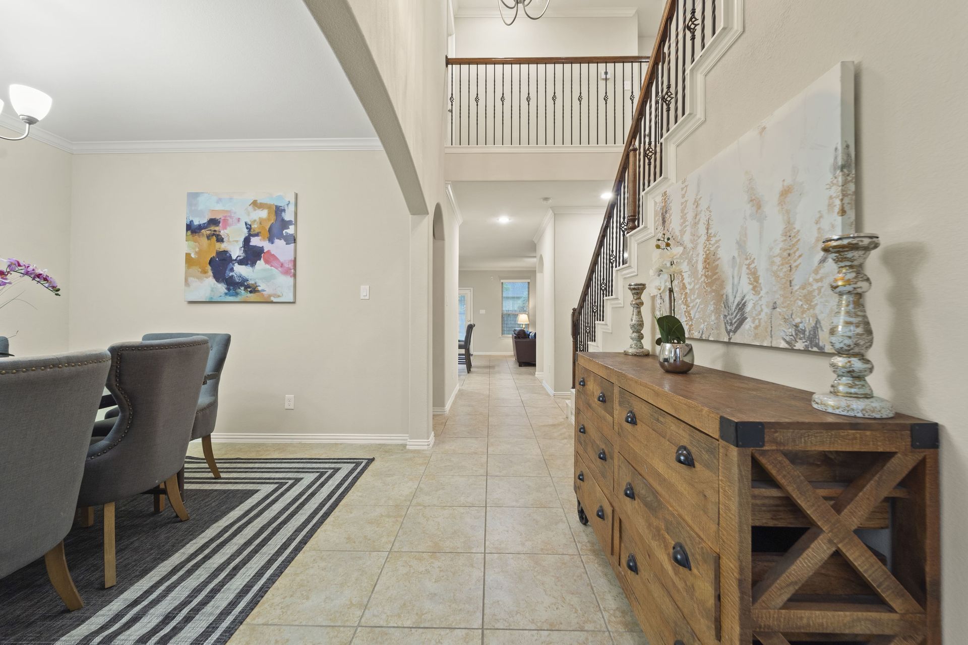 Entryway with wooden console table, staircase, and dining area featuring a table and chairs. The walls are beige.