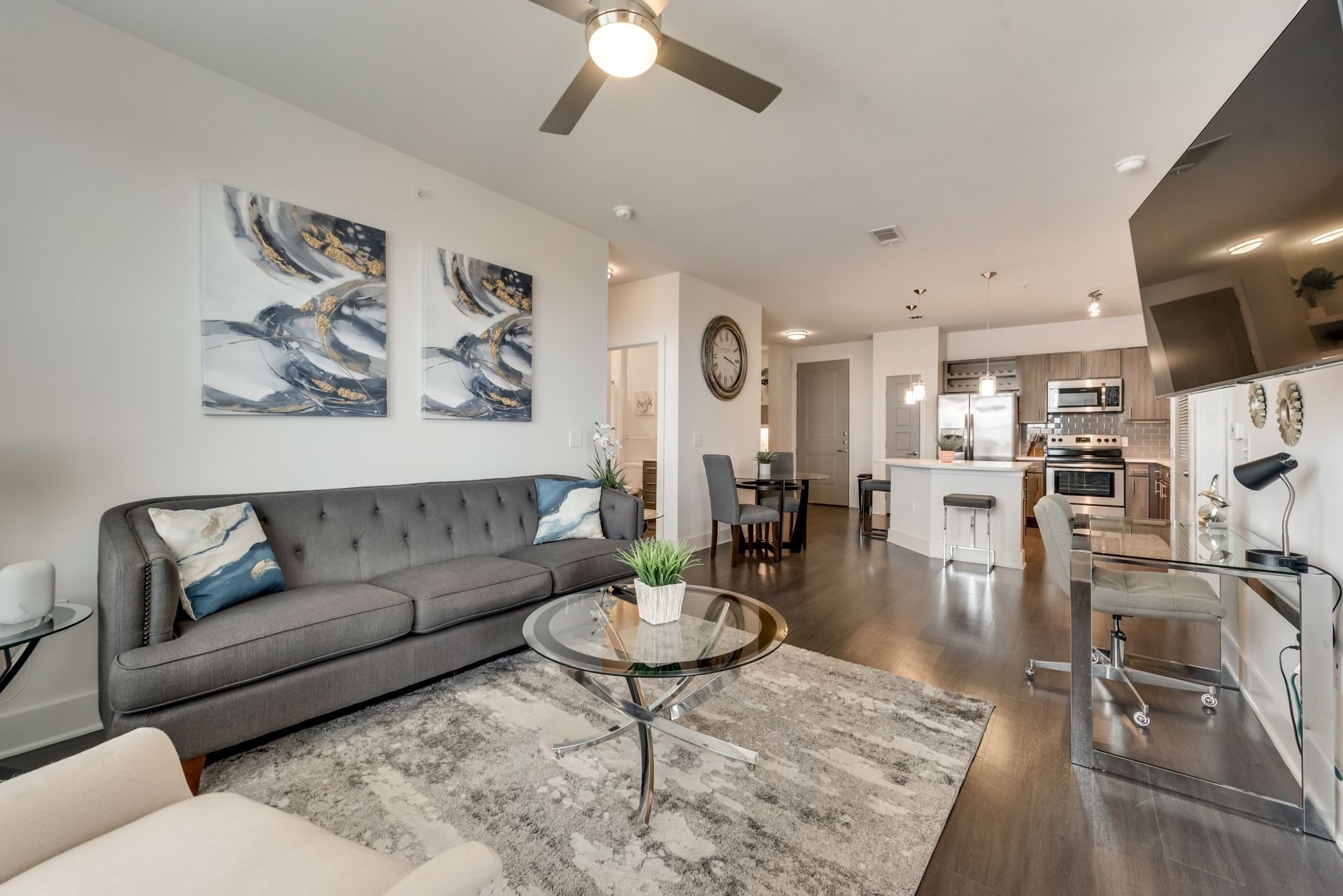 A living room with a couch , coffee table , television and ceiling fan.