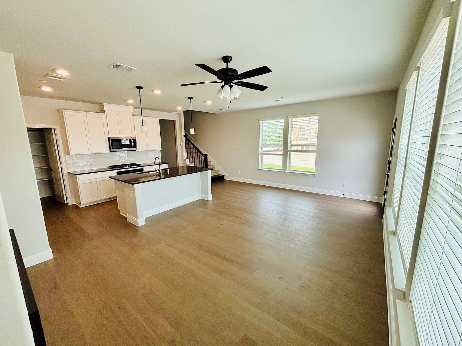 Empty interior with tiled floor, arched doorway leading to stairs, chandelier, windows, and front door.