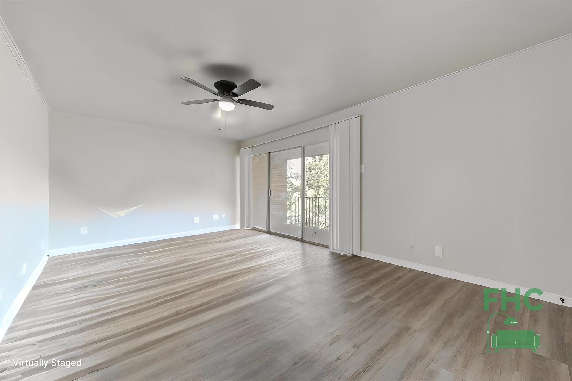 Empty living room with wood-look flooring, white walls, a ceiling fan, and sliding glass doors to a balcony.