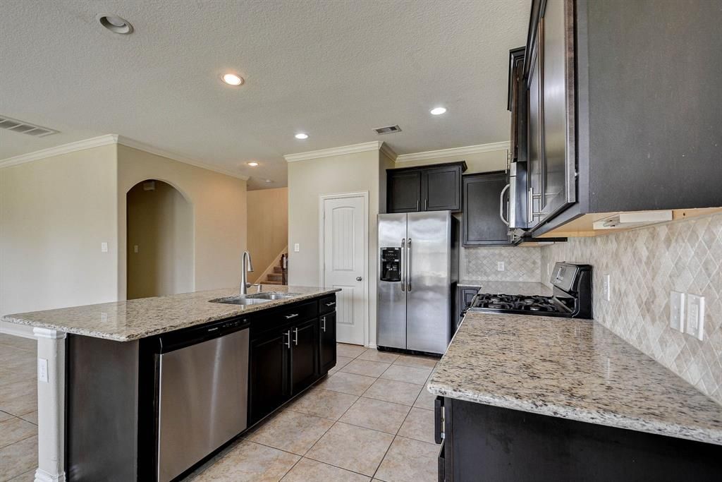 Spacious kitchen with a large island, stainless steel appliances, and granite countertops. Neutral color scheme.