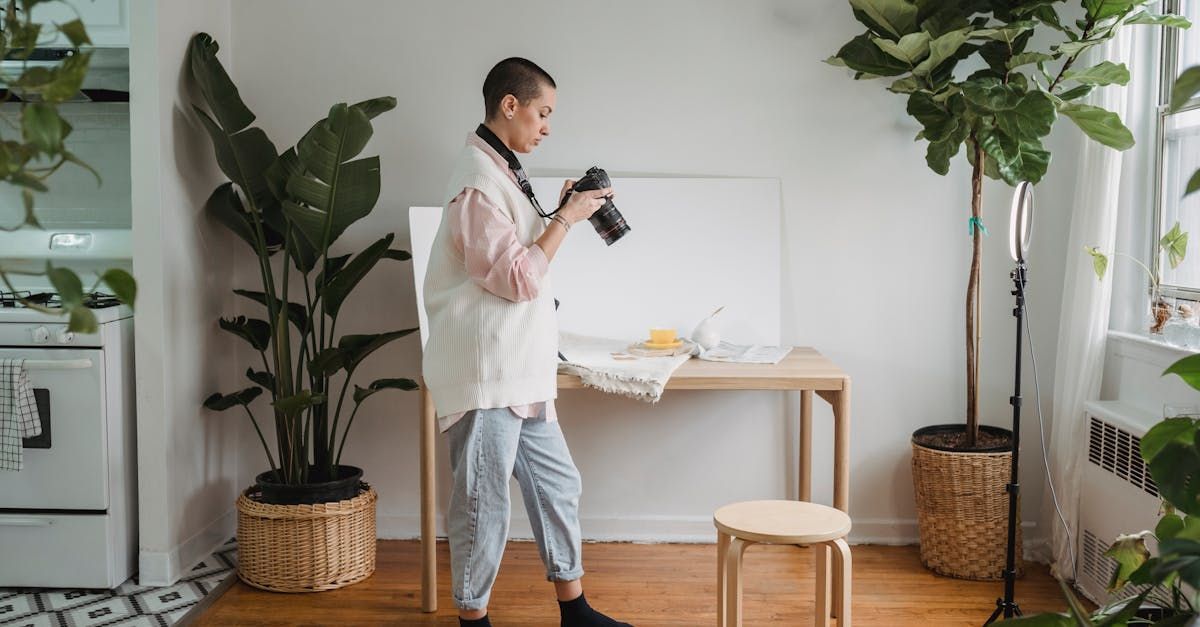 A person is photographing a food scene set up on a table in a bright room, surrounded by plants.