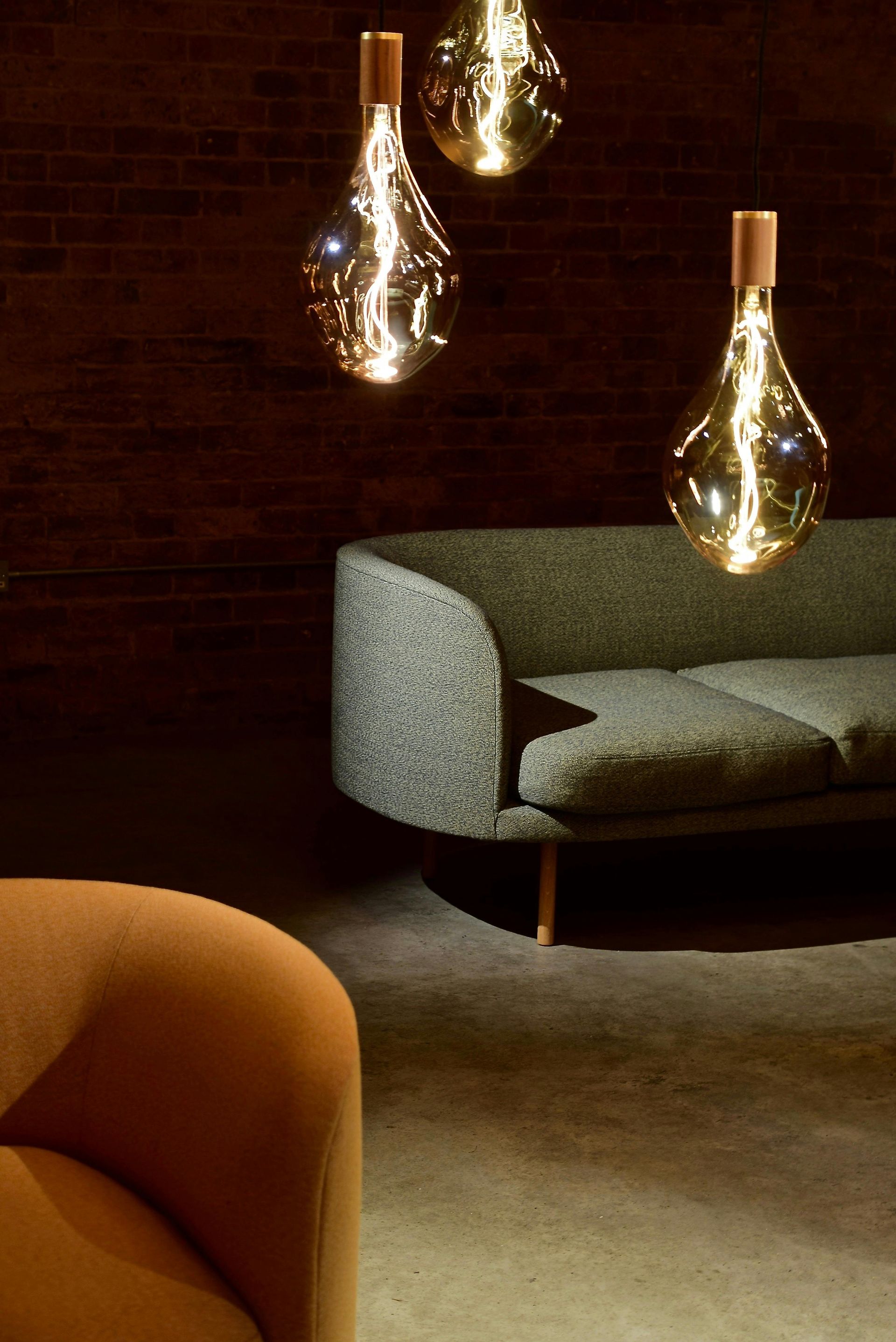 A living room with a couch and two lights hanging from the ceiling