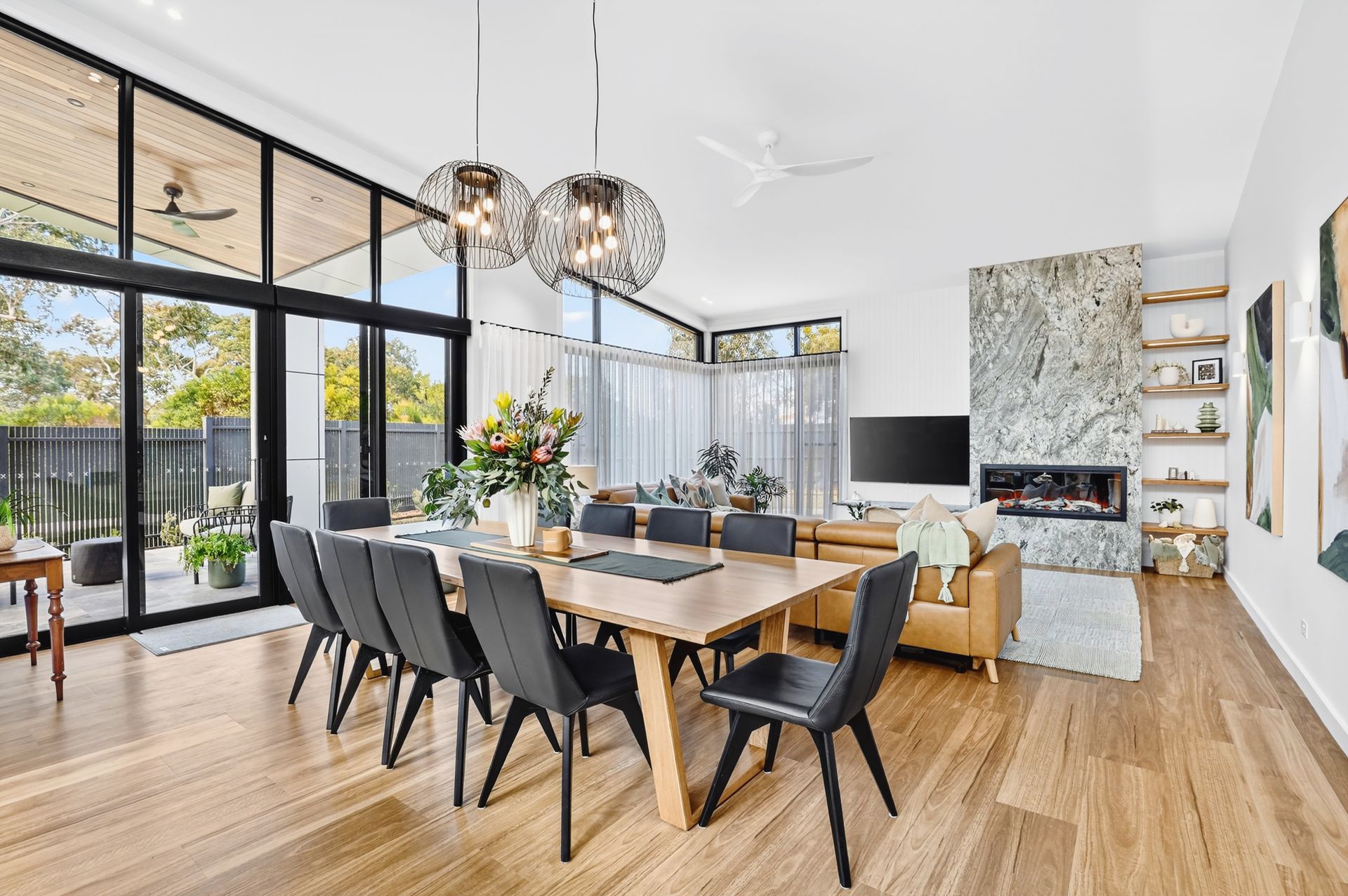 Dining room with wooden table, black chairs, large windows, and a fireplace.