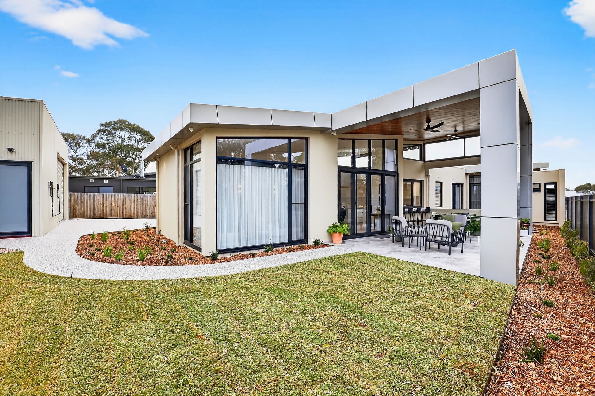 Modern, single-story house with a small patio and a lawn, sunny day.