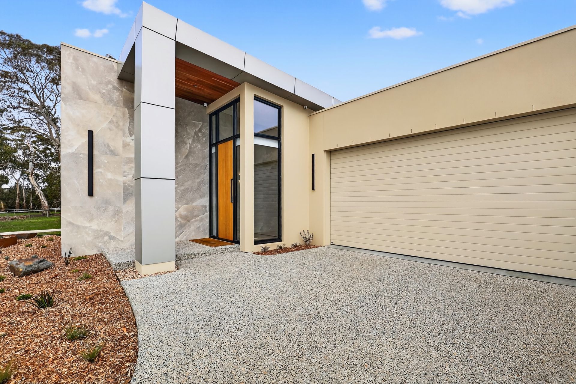 Modern home with a grey gravel driveway and beige garage door.