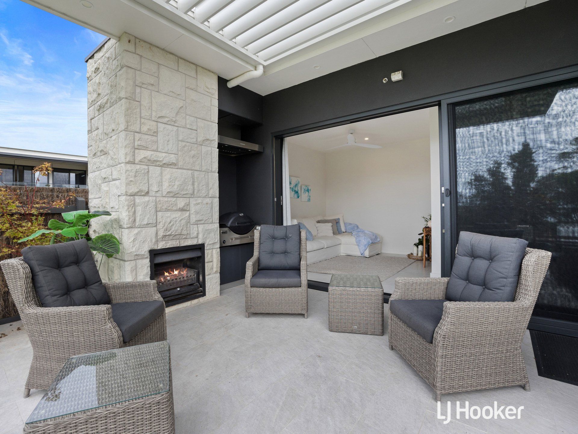 A patio with chairs , a table and a fireplace.