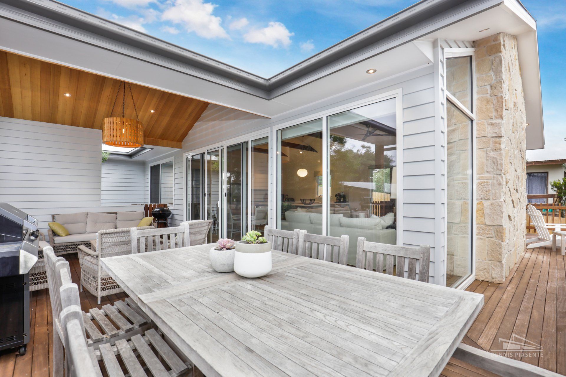 There is a table and chairs on the deck of a house.