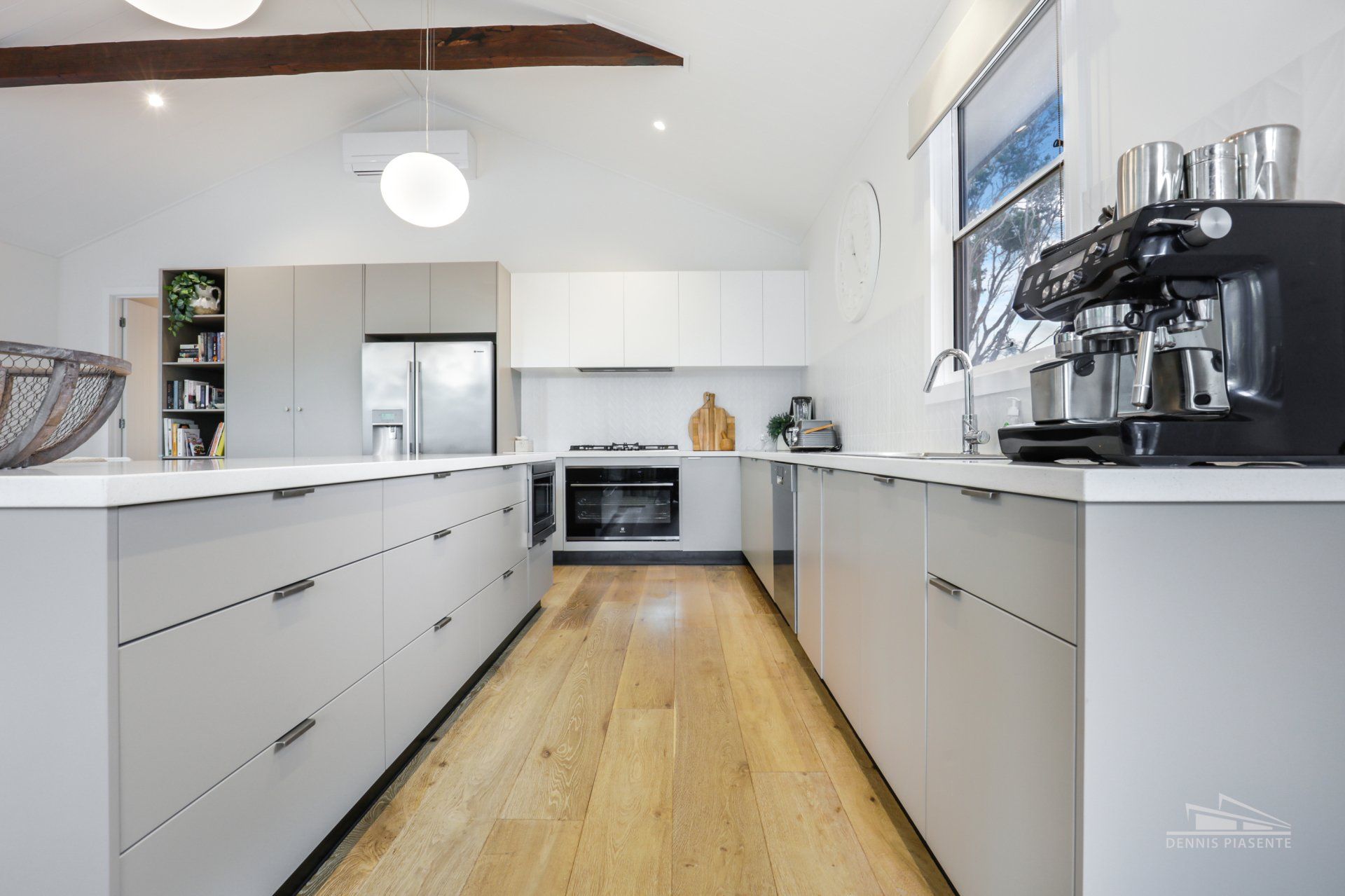 A kitchen with white cabinets and wooden floors and a coffee maker.