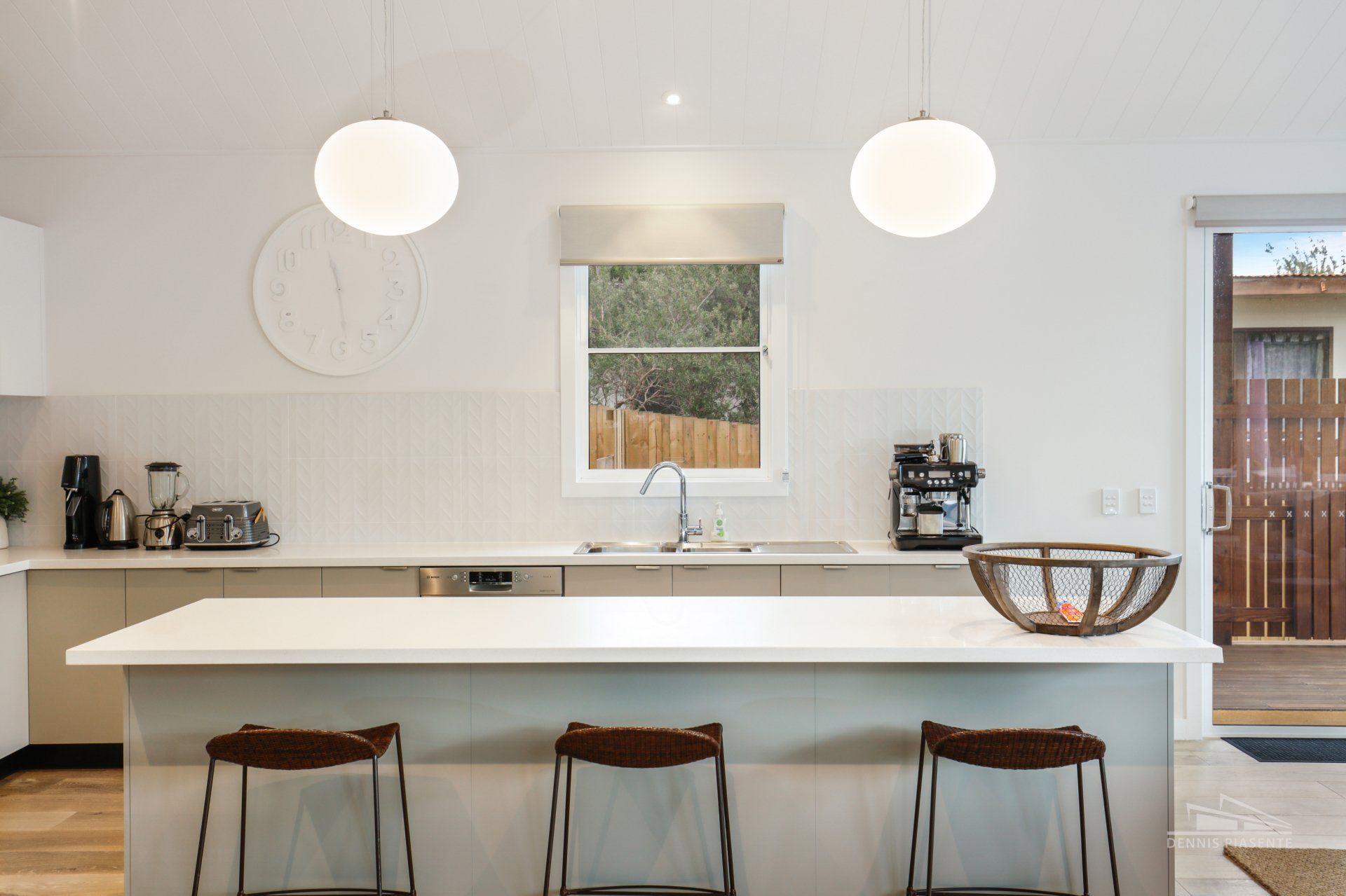 A kitchen with a large island , stools , a sink and a window.