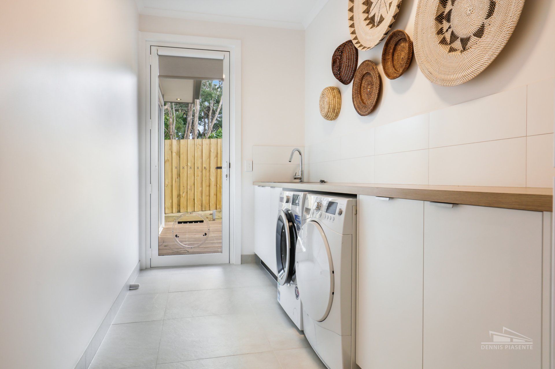 A laundry room with a washer and dryer and baskets on the wall.