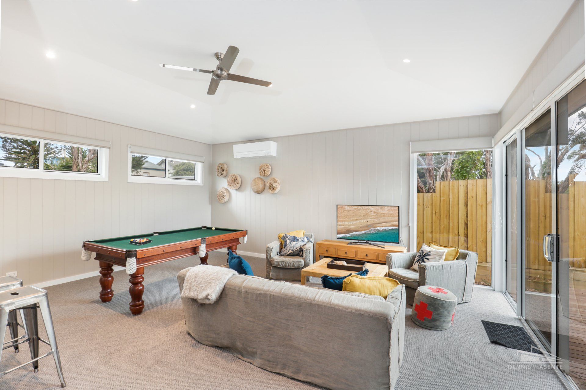A living room with a pool table and a ceiling fan.