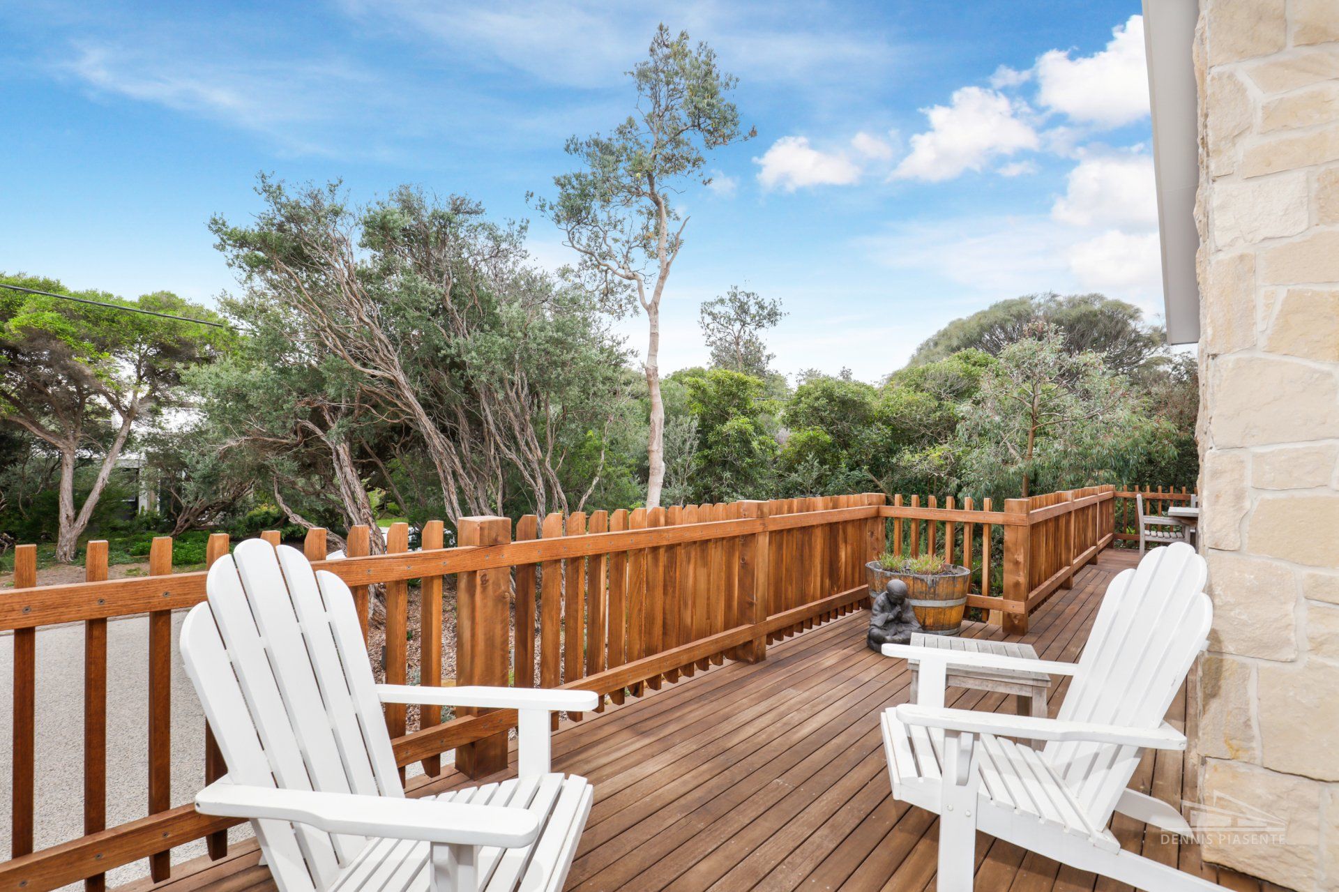 Two white chairs are sitting on a wooden deck next to a wooden fence.