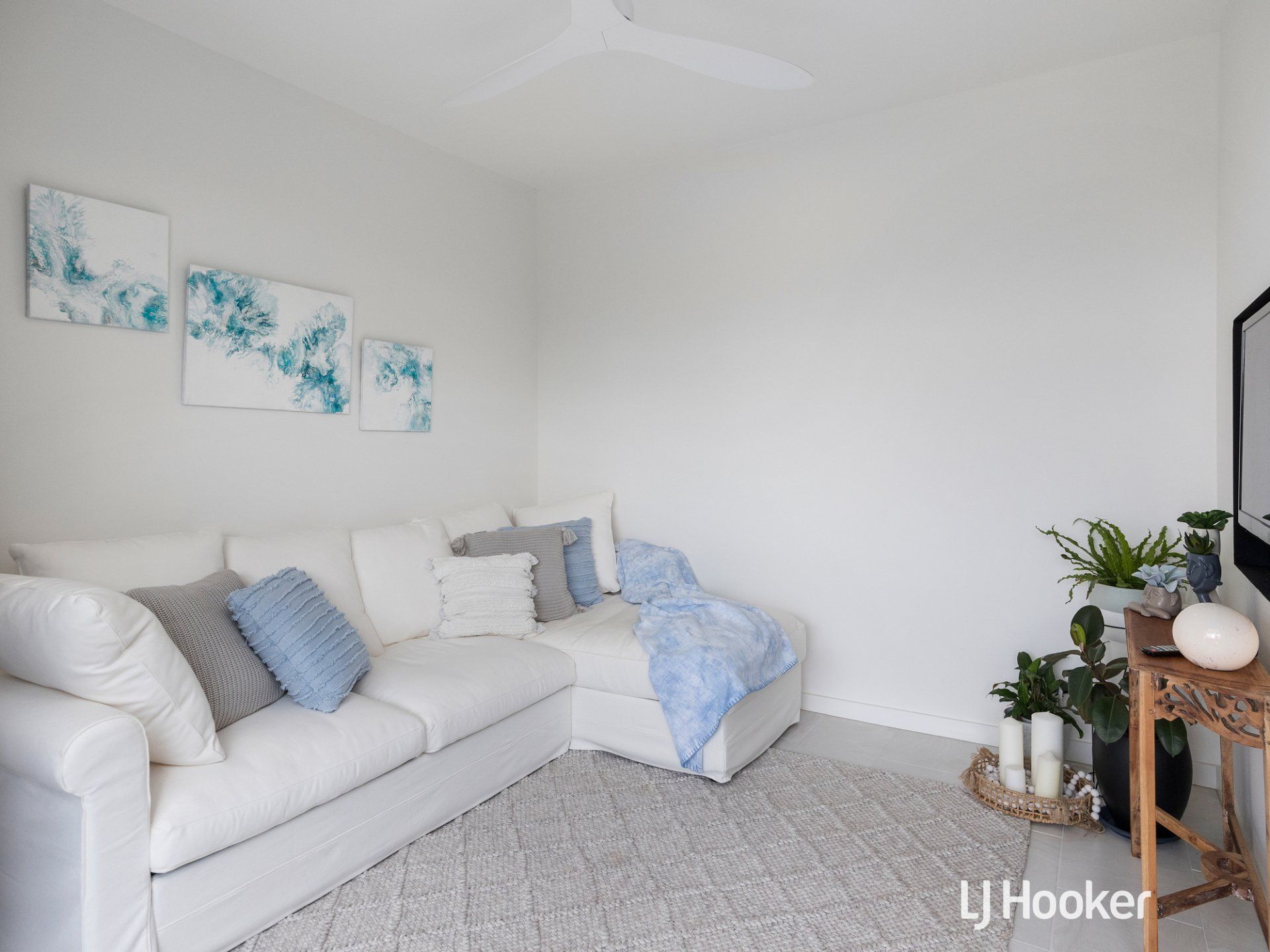 A living room with a white couch and blue pillows.