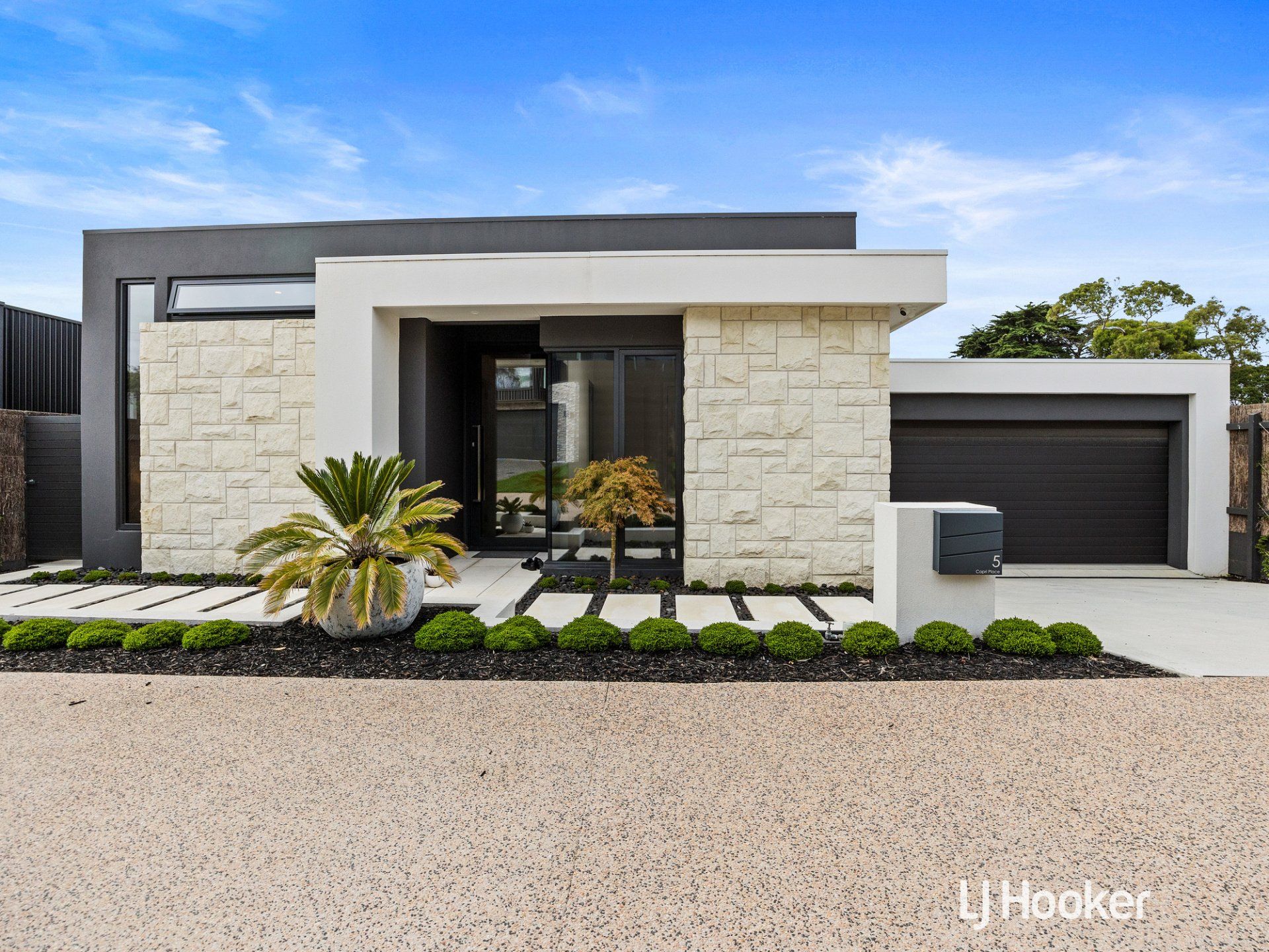A modern house with a stone facade and a black garage door