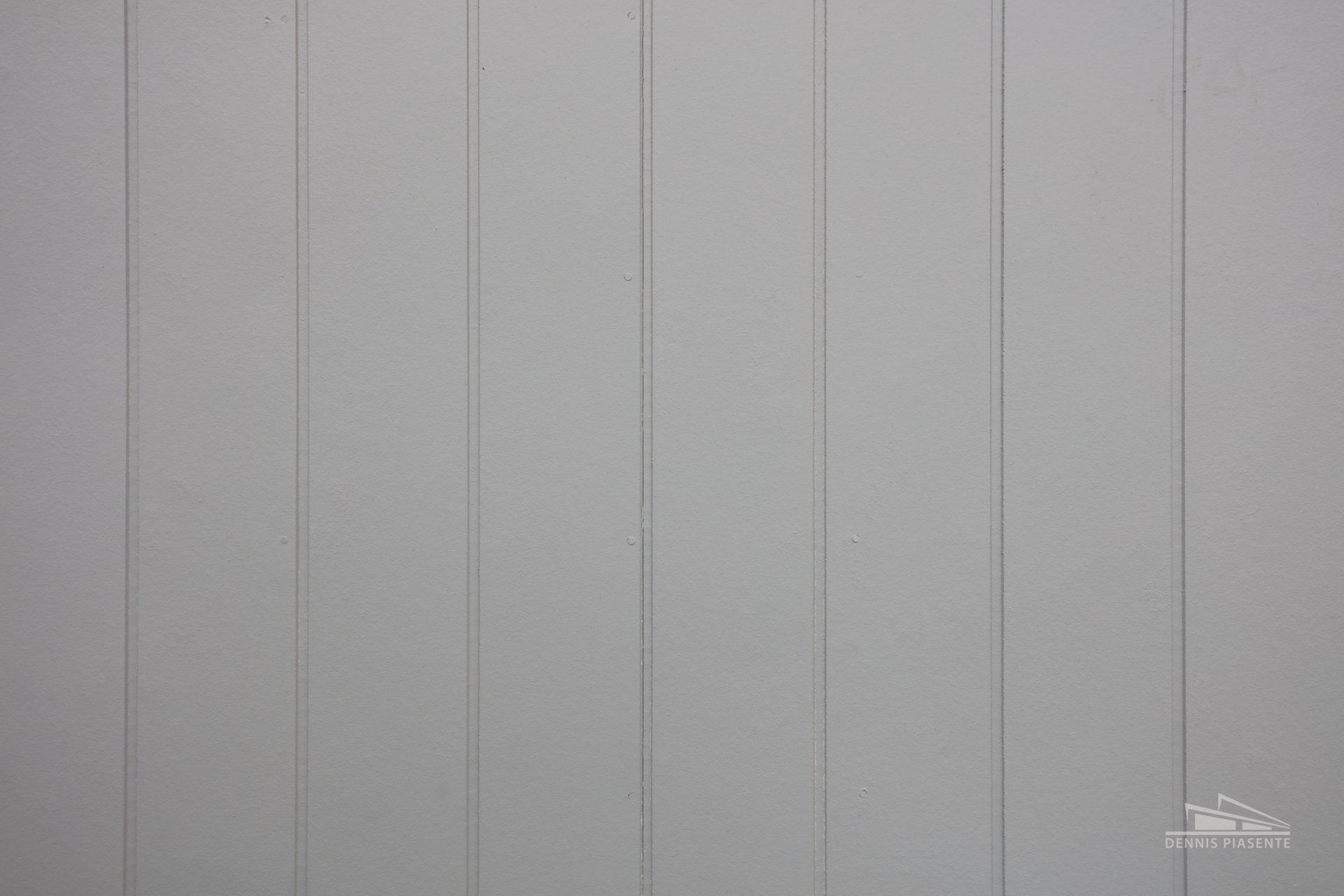 A close up of a white wooden wall with vertical boards.