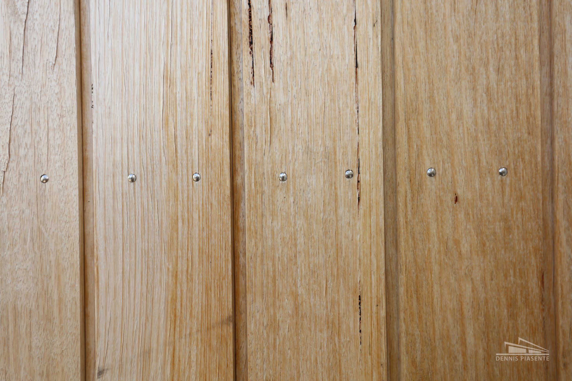 A close up of a wooden wall with nails in it.