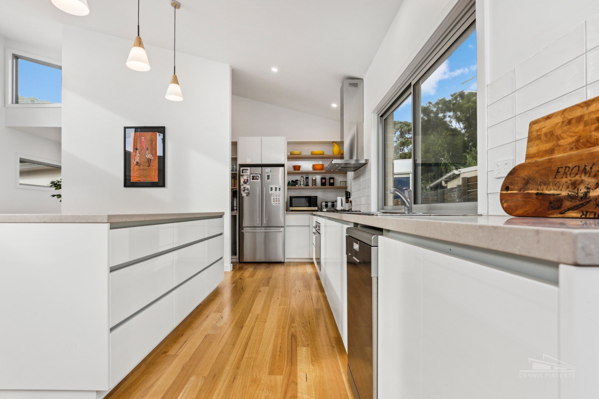 A kitchen with white cabinets , stainless steel appliances and hardwood floors.