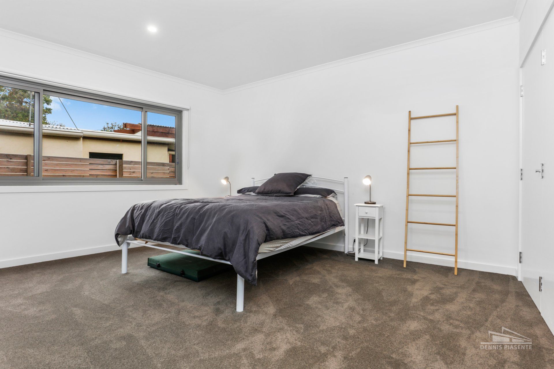 A bedroom with a bed , nightstand , and ladder.