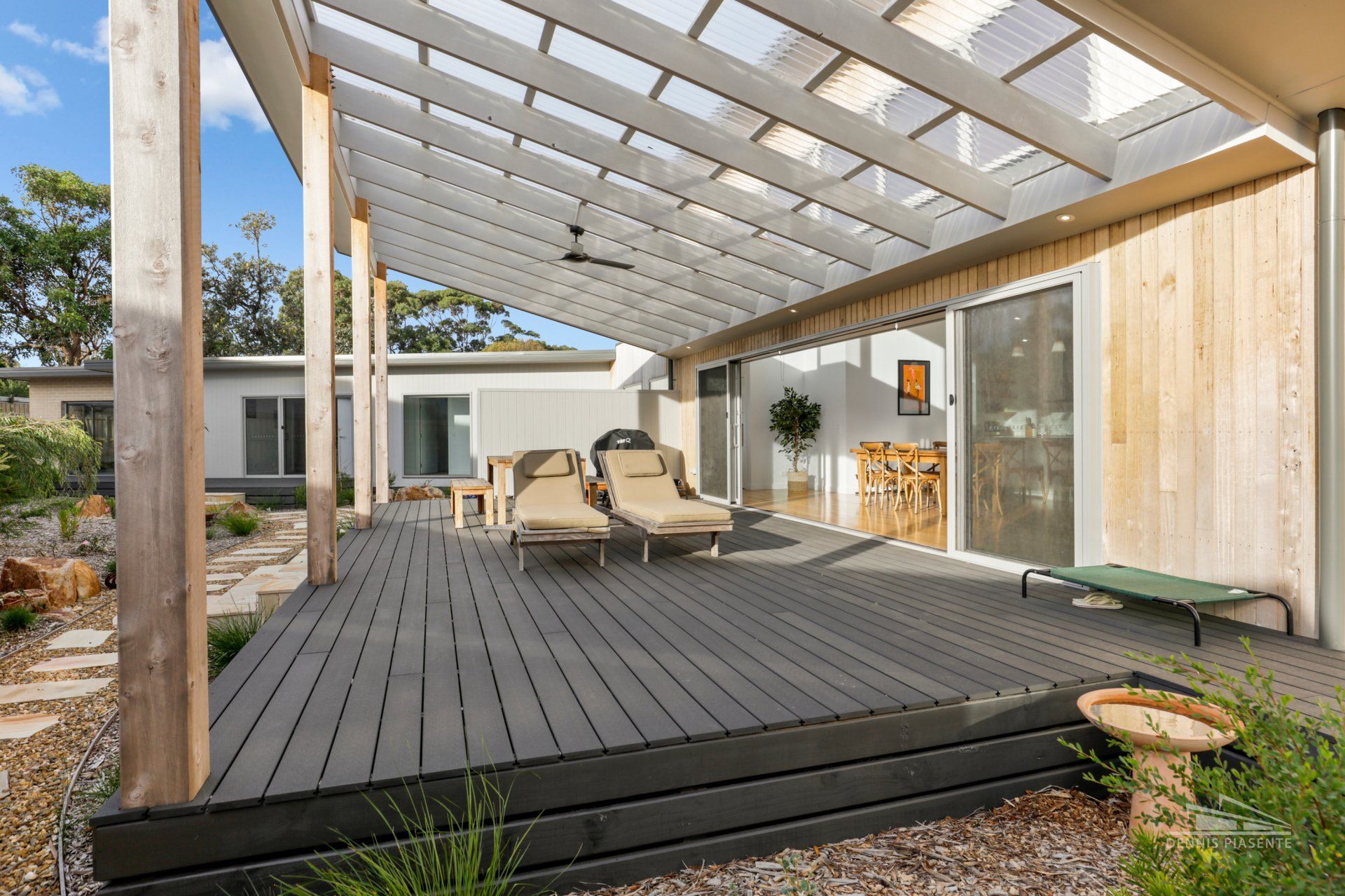 There is a large deck with a pergola and chairs on it.