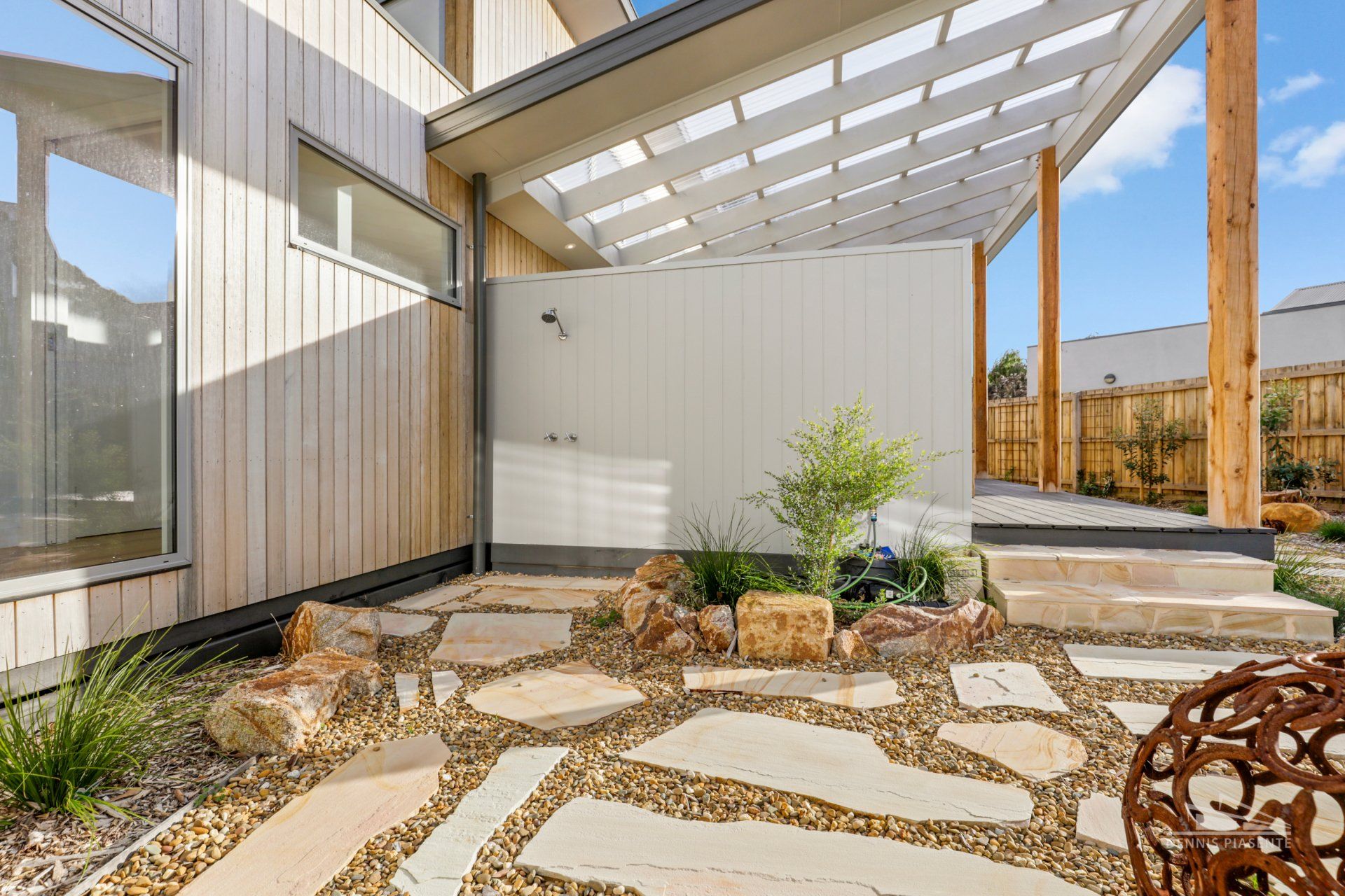A stone walkway leading to a house with a pergola.