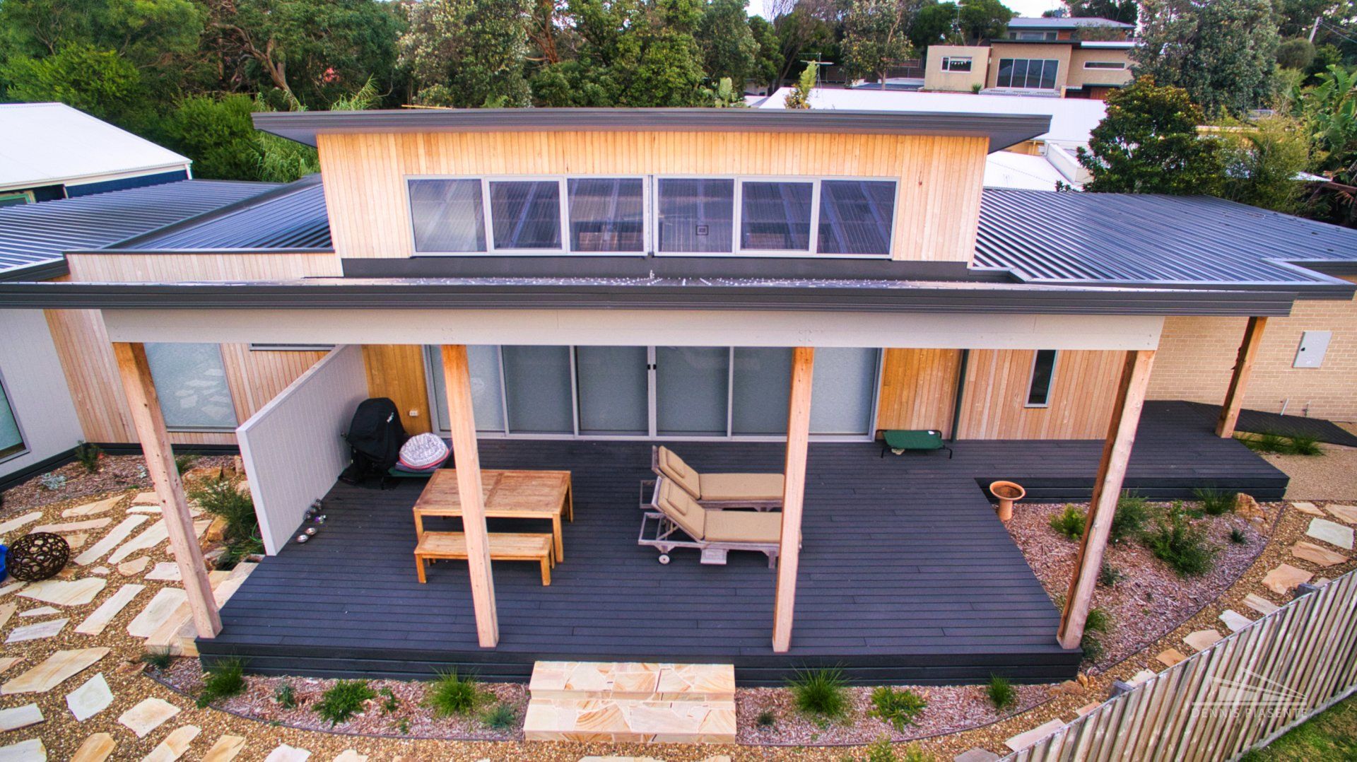 An aerial view of a house with a deck and chairs on it.
