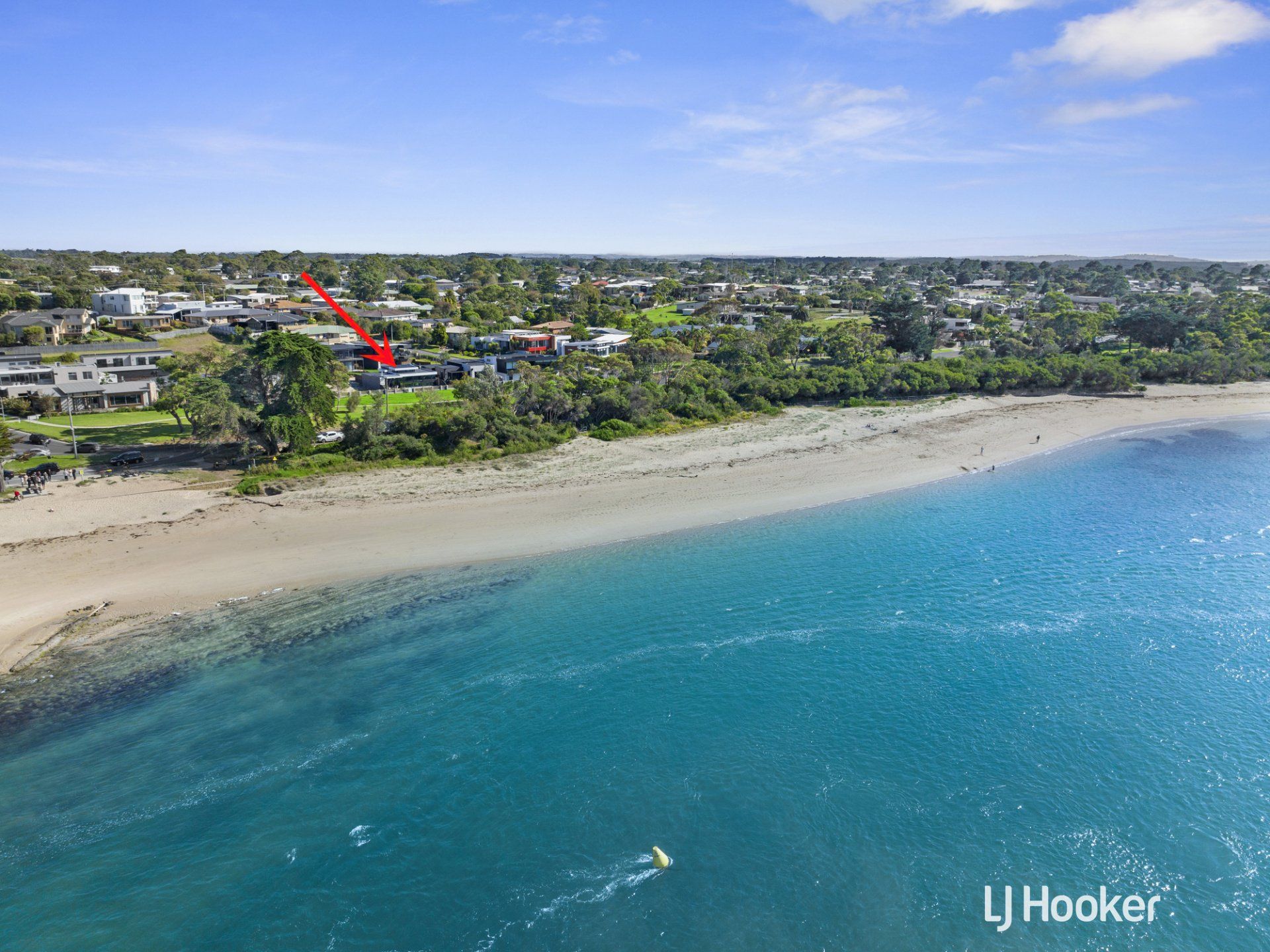 An aerial view of a beach with a red arrow pointing to a house.