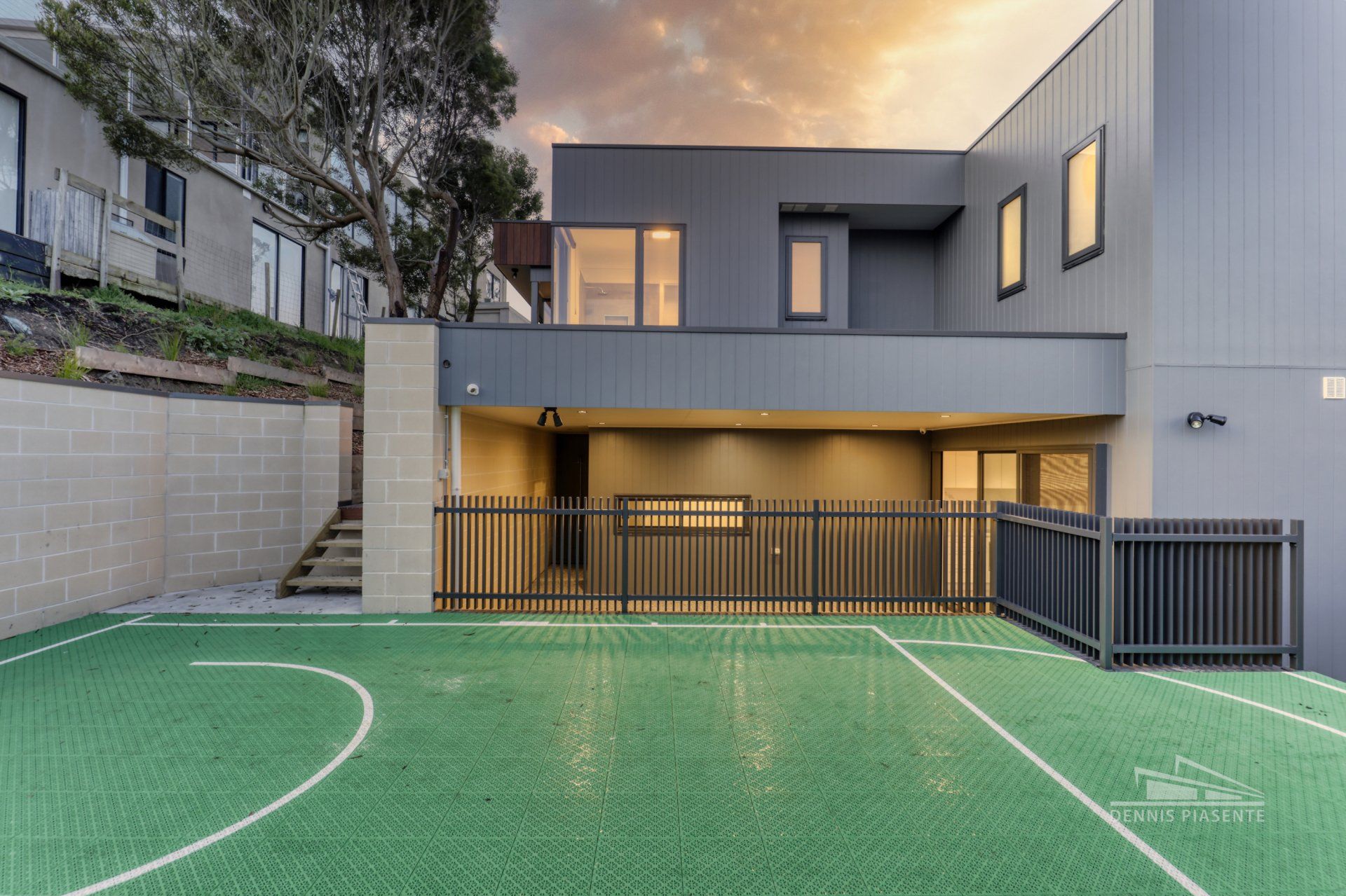 A large house with a basketball court in front of it.