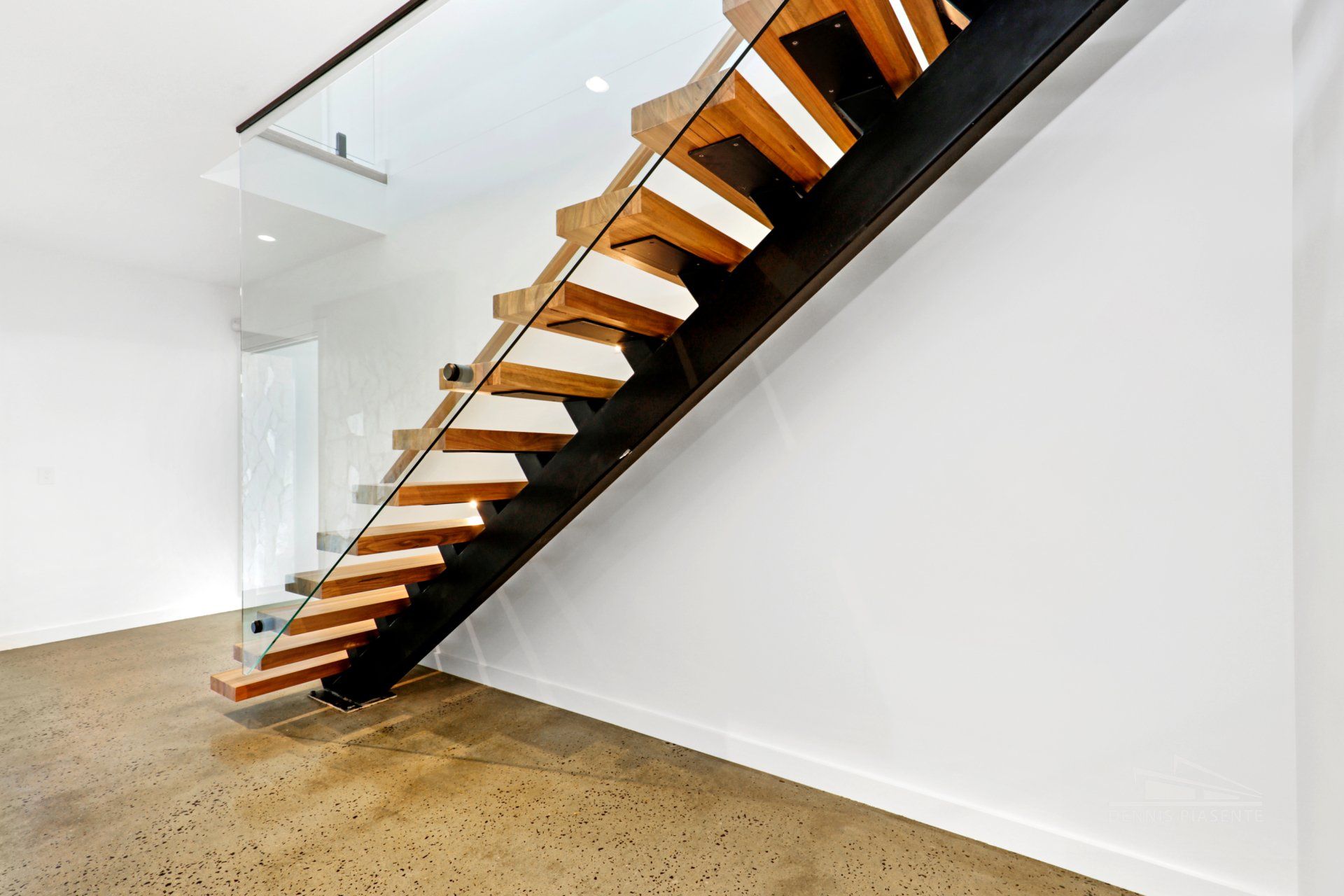 A wooden staircase with a glass railing in a room.