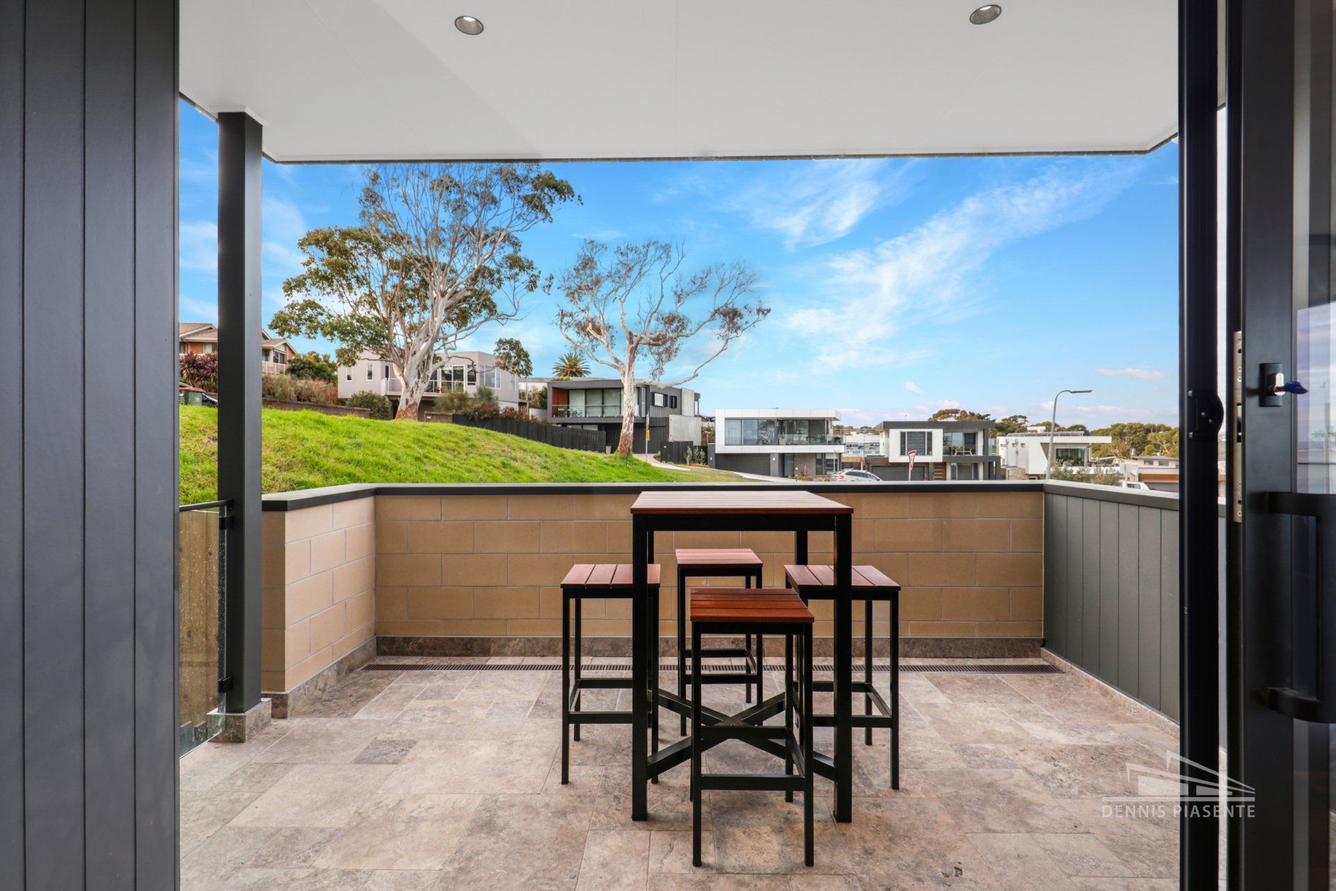 A balcony with a table and stools and a view of a city.
