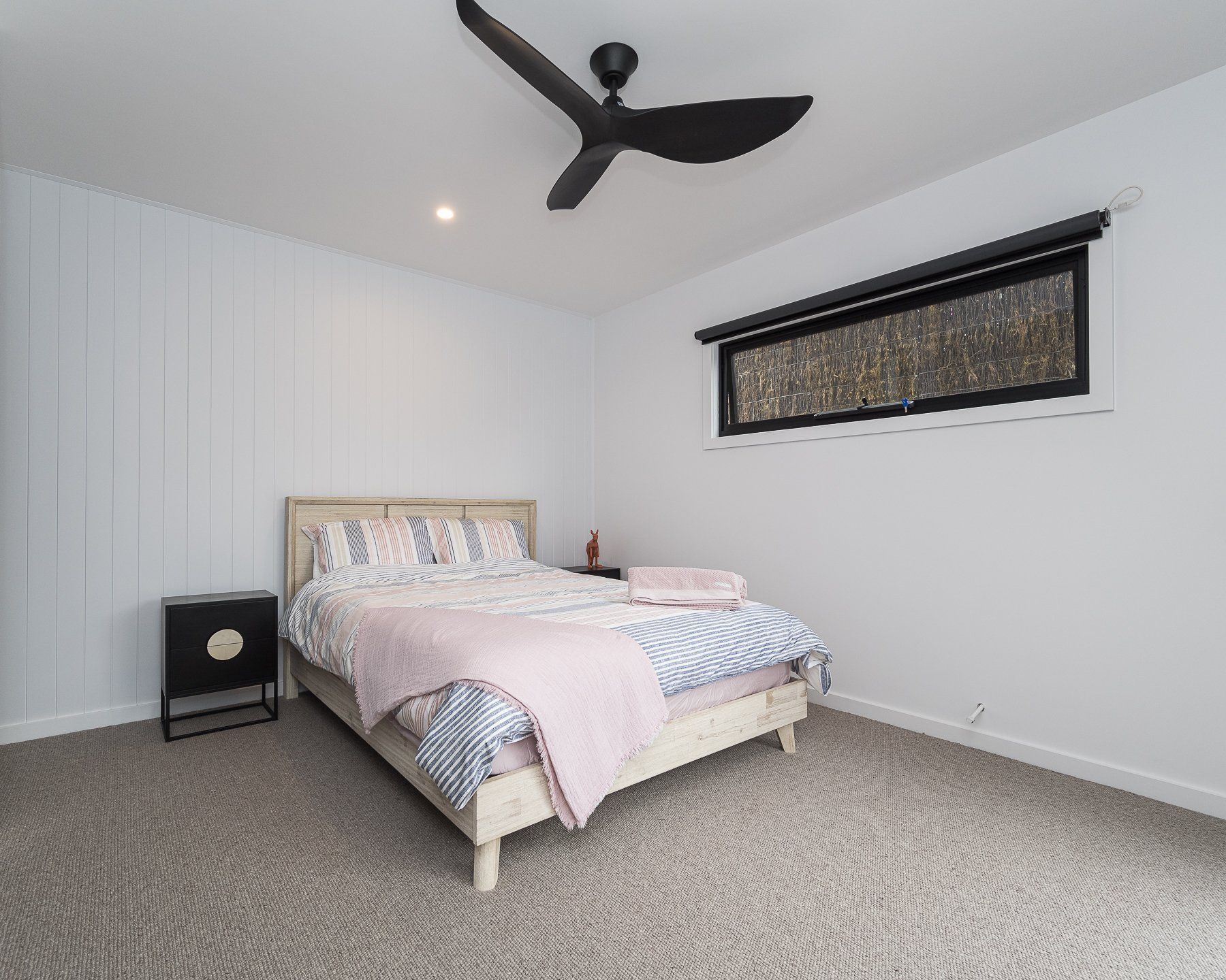 A bedroom with a bed , nightstand , and ceiling fan.