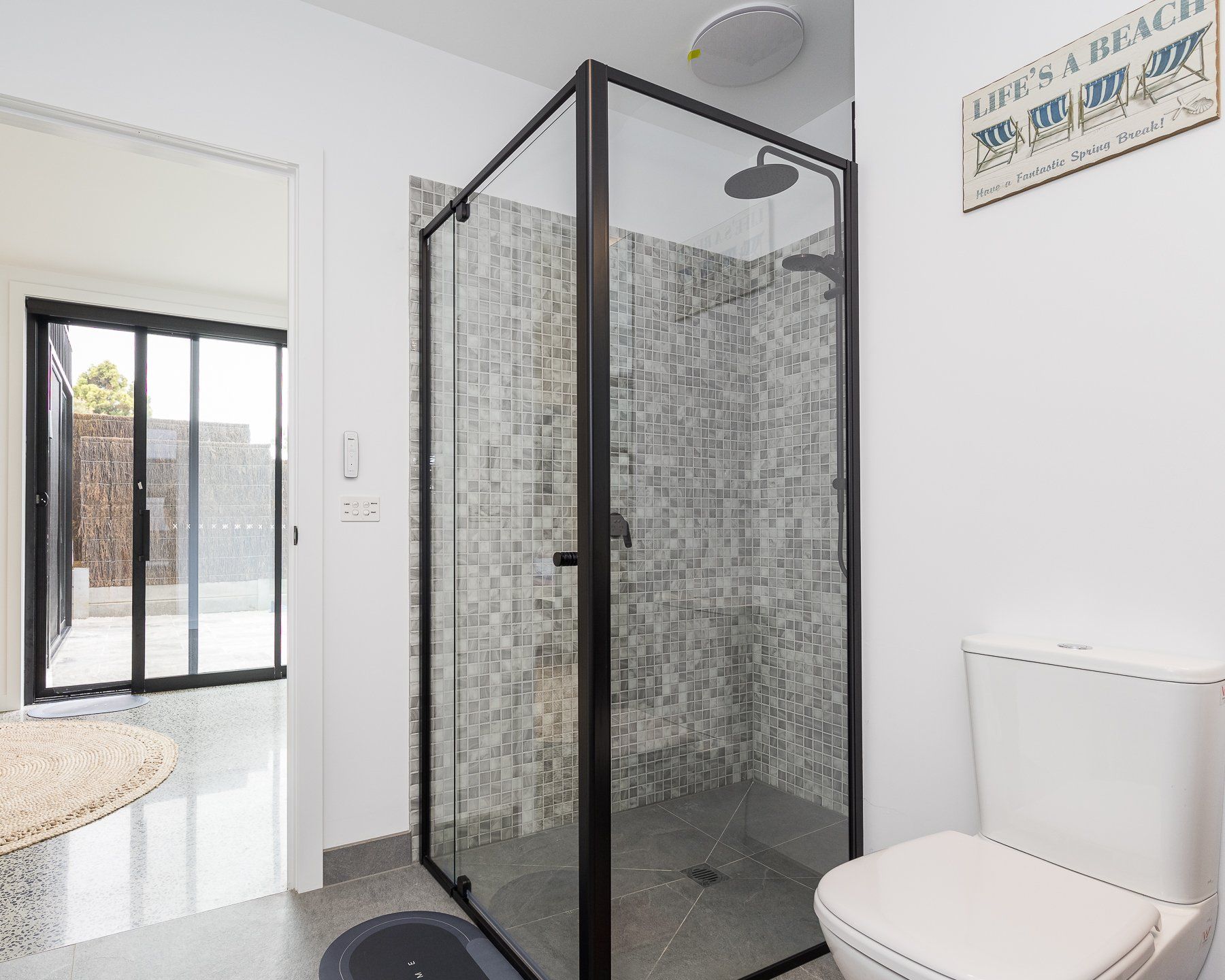 A bathroom with a toilet , shower and sliding glass doors.