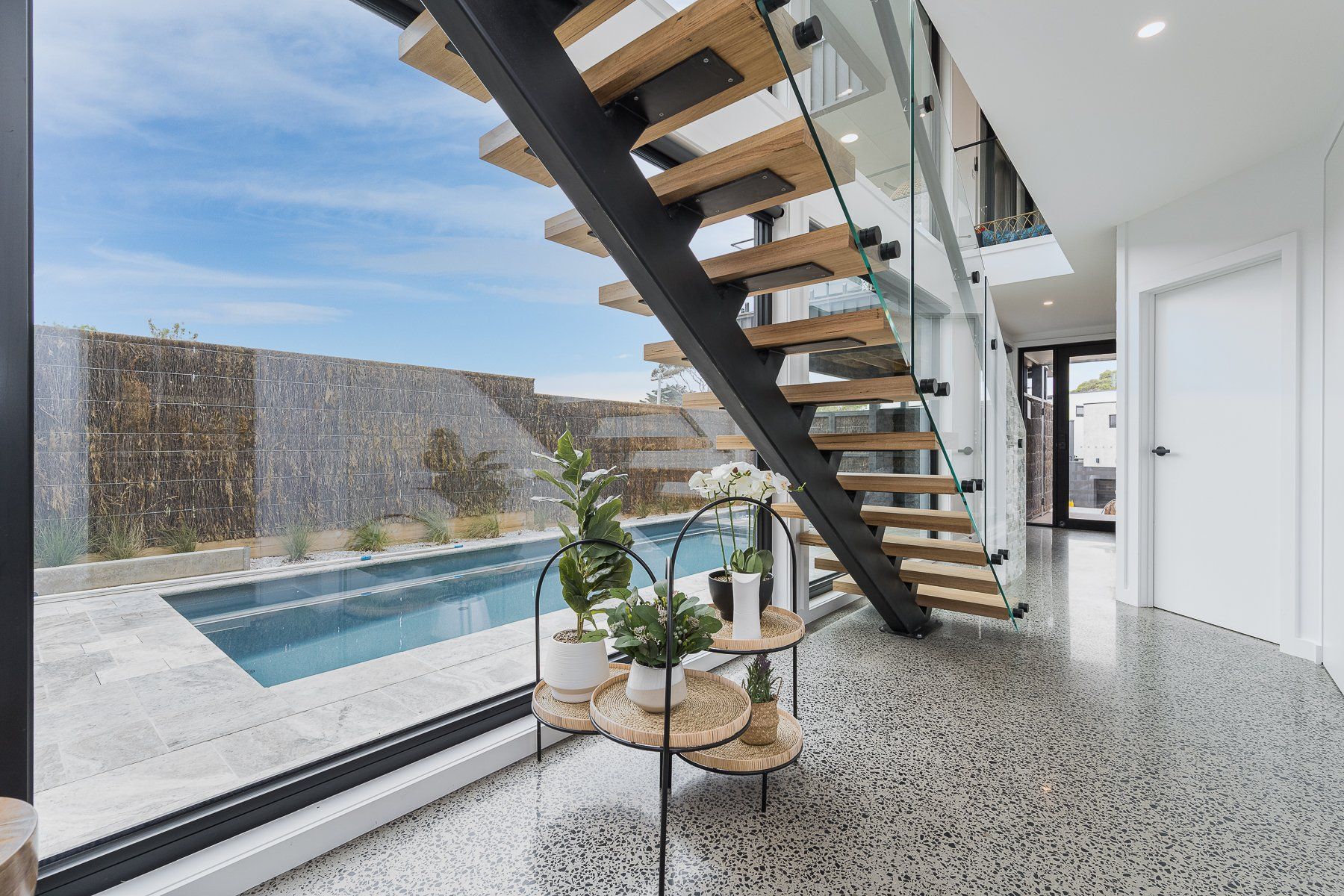 A modern staircase leading to a swimming pool in a house.