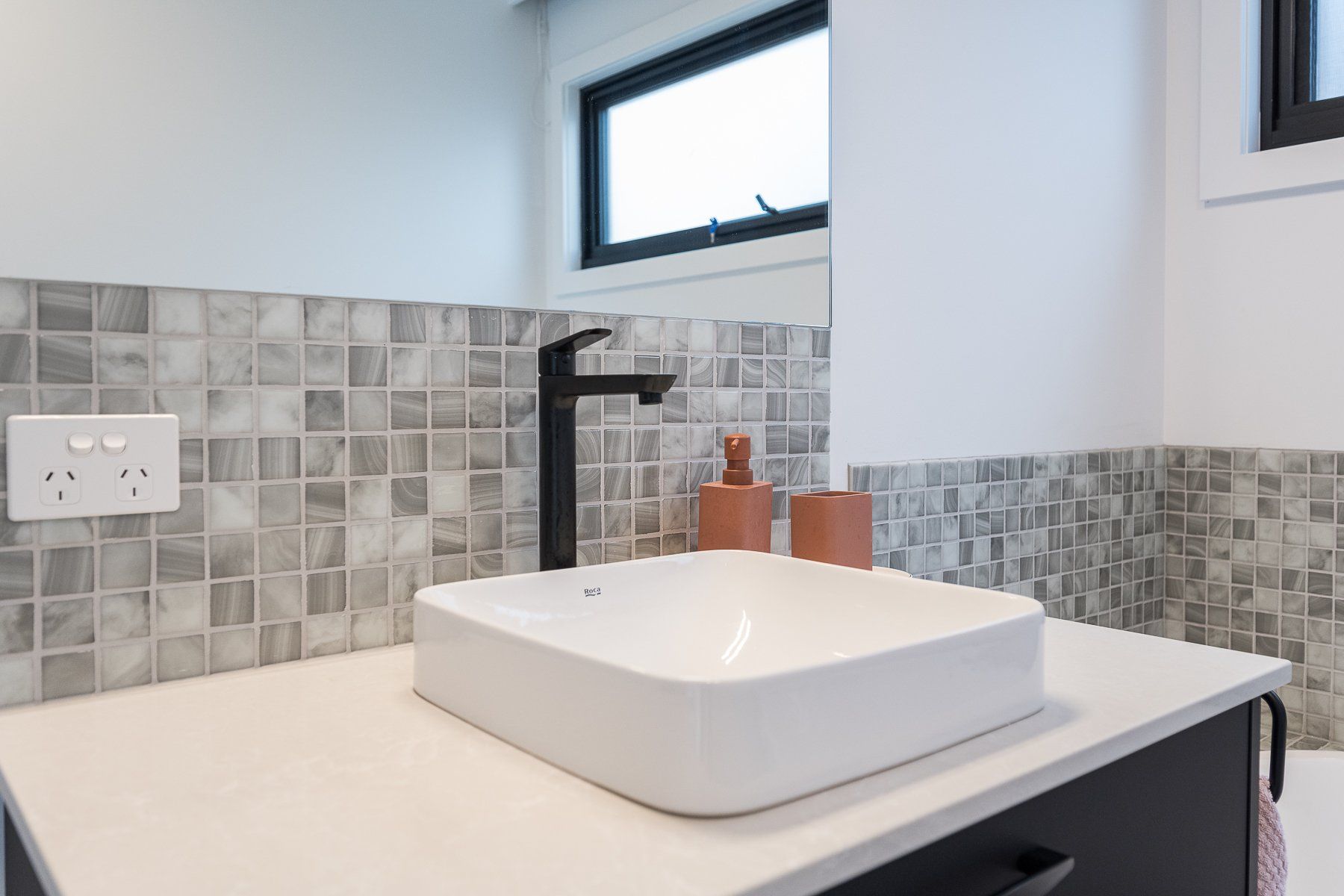 A bathroom sink with a black faucet and a window.