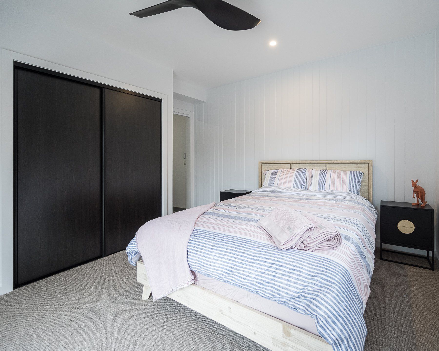 A bedroom with a bed , nightstand , closet and ceiling fan.
