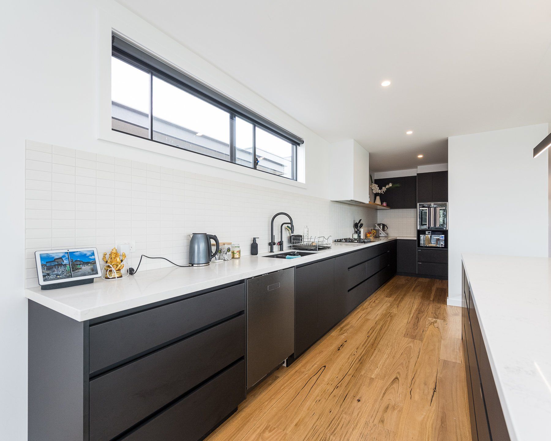 A kitchen with black cabinets and wooden floors and a large window