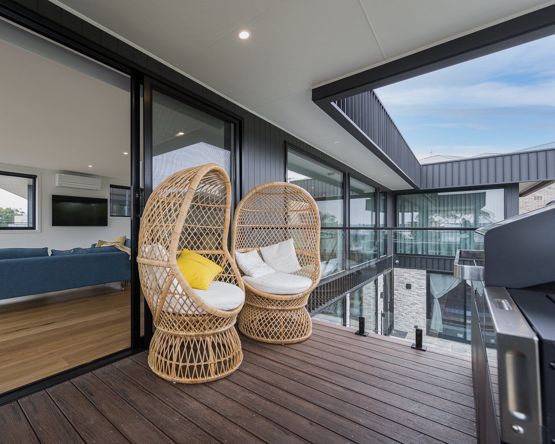 A balcony with two wicker chairs and a grill.