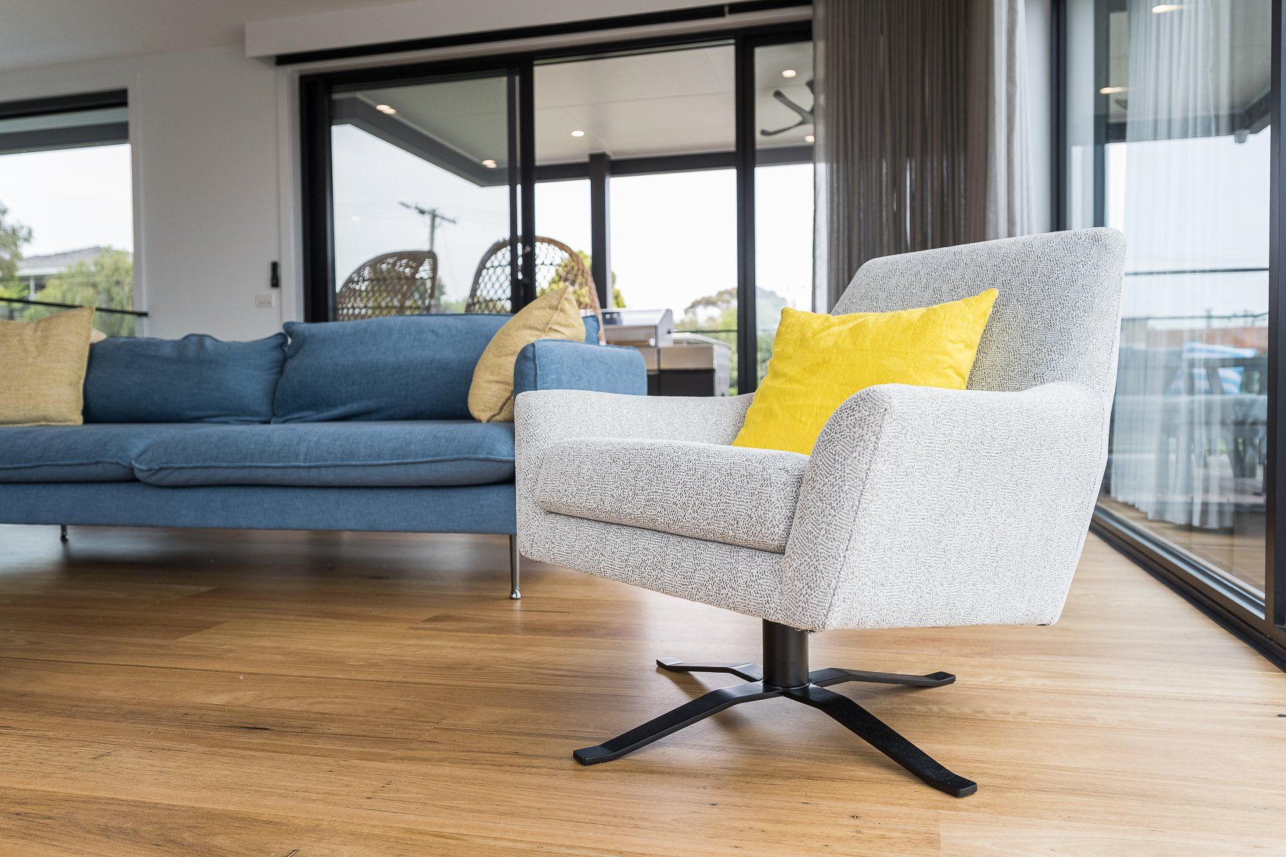 A living room with a blue couch and a white chair.