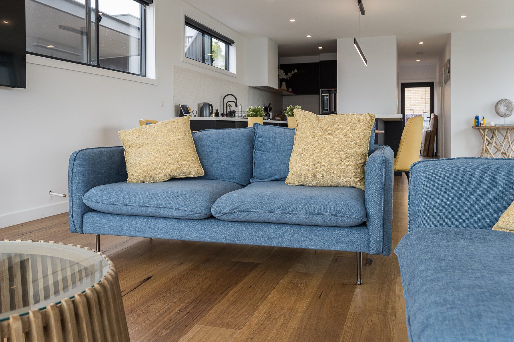A living room with a blue couch and yellow pillows.