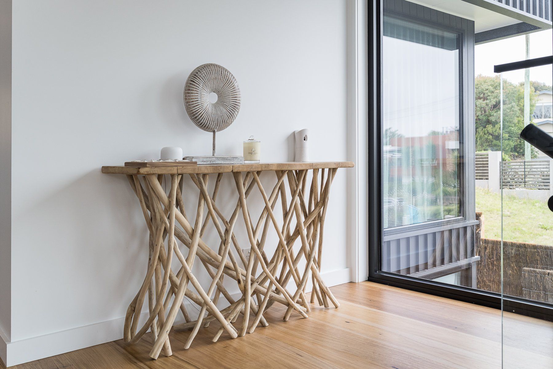 A wooden table is sitting in front of a large window in a room.