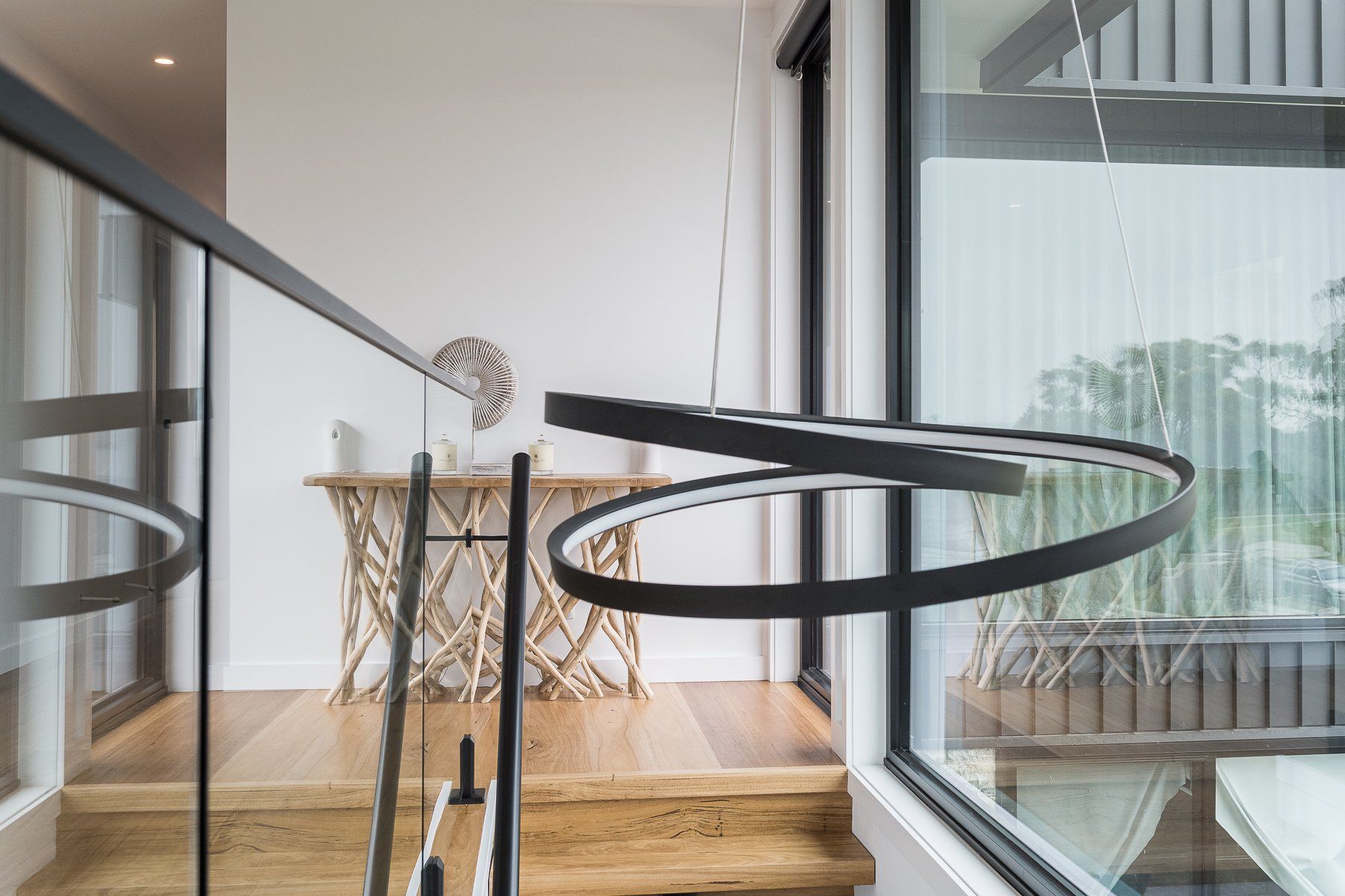 A staircase with a glass railing and a table in the background.