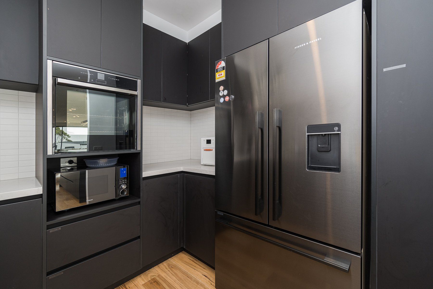 A kitchen with stainless steel appliances and black cabinets.