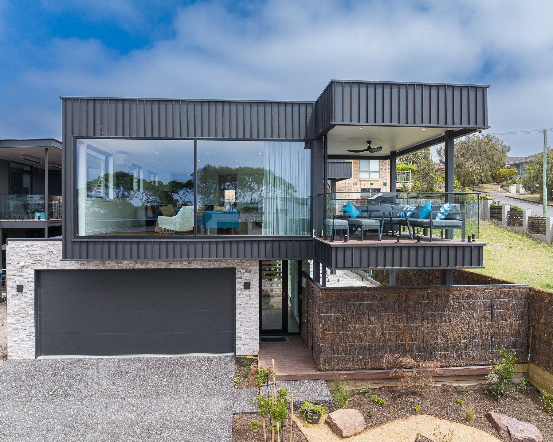 An aerial view of a modern house with a large garage and a balcony.