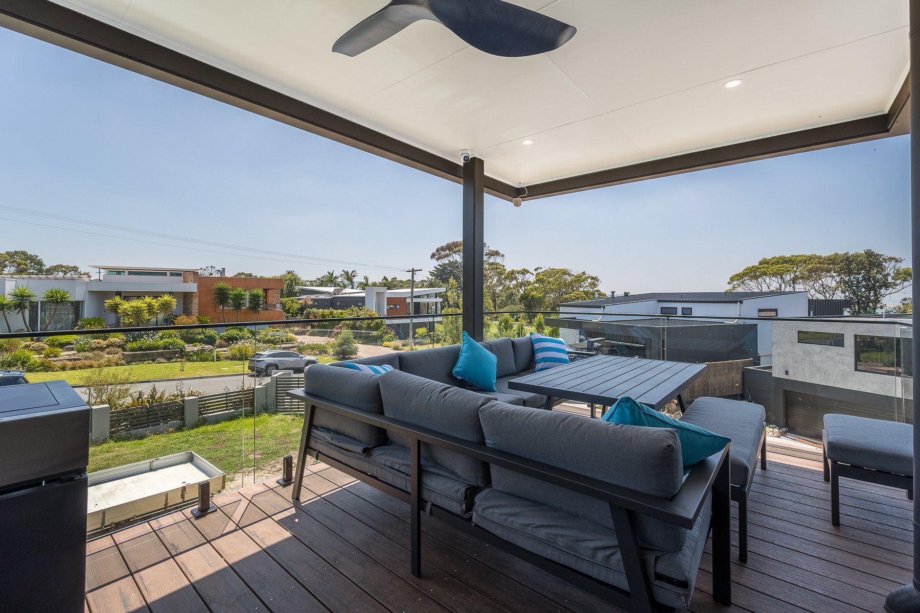 A patio with a couch , table , chairs and a ceiling fan.