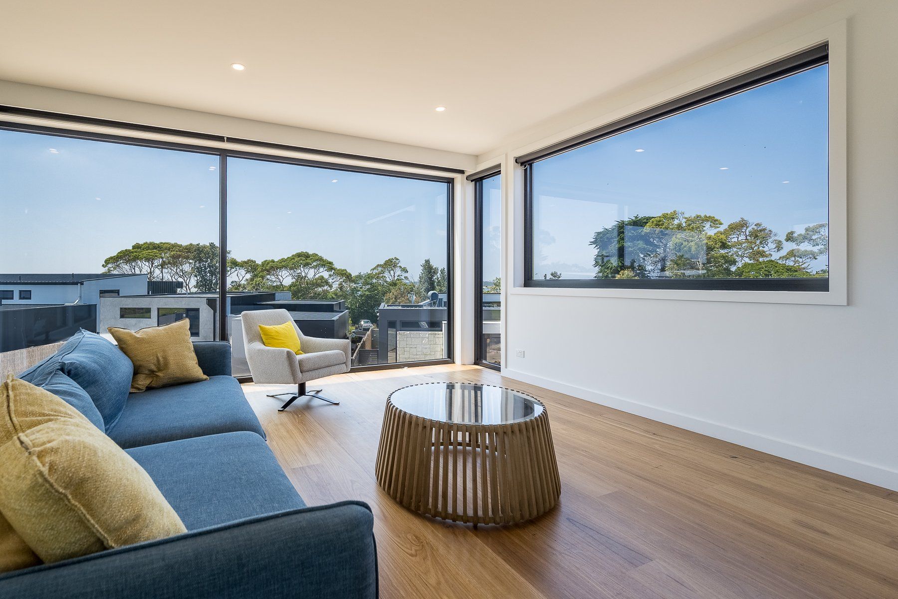 A living room with a couch , chair , coffee table and large windows.