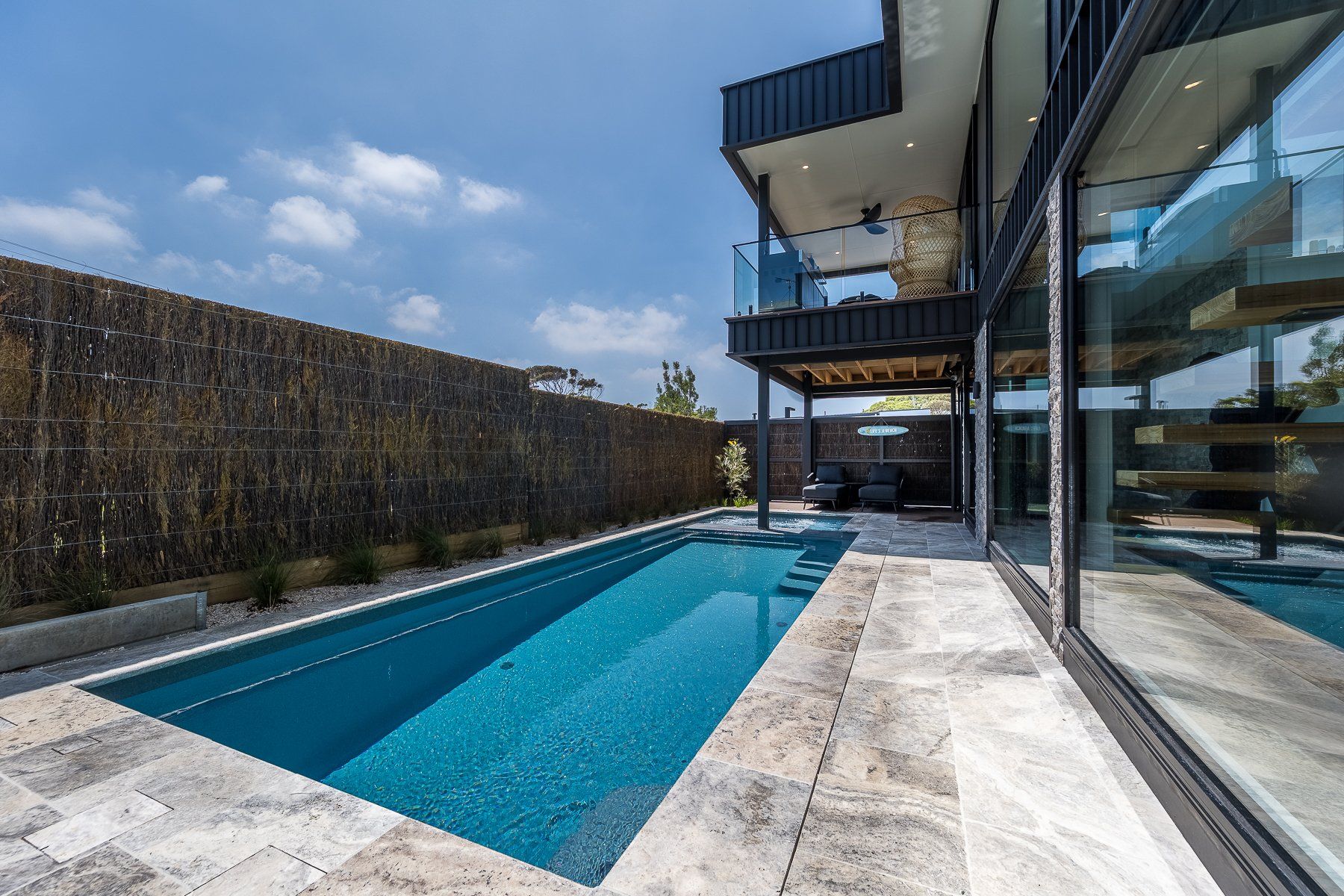 There is a large swimming pool in the backyard of a house.