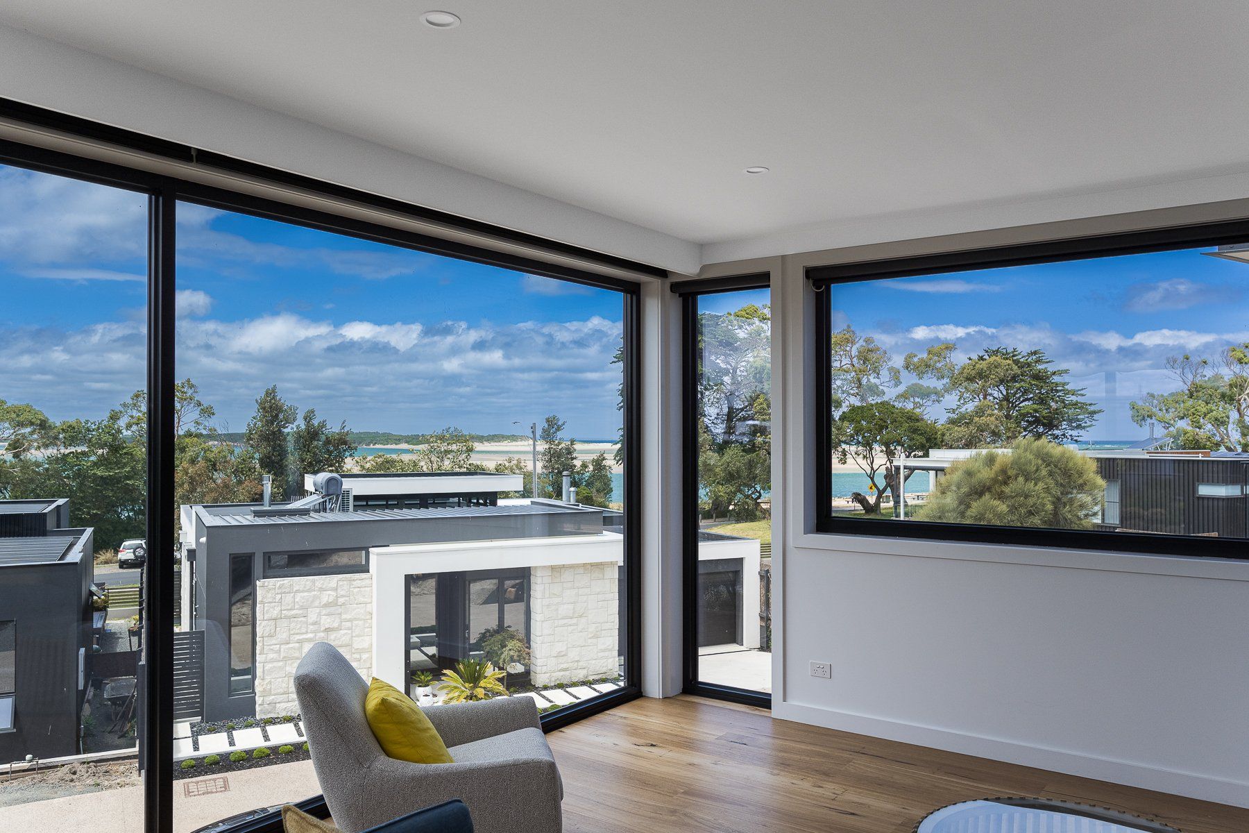 A living room with a lot of windows and a view of the ocean.