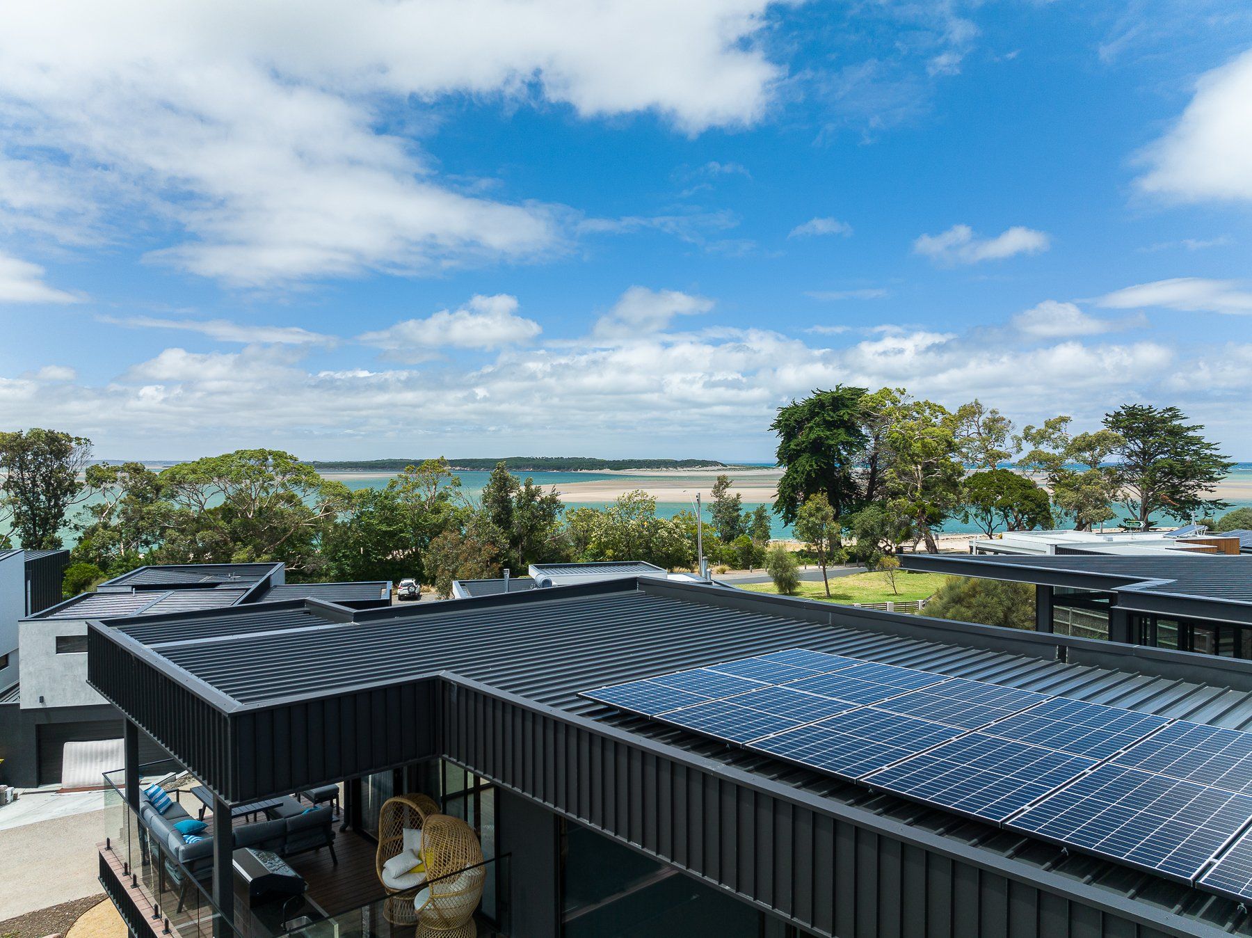 A house with solar panels on the roof and a view of the ocean.