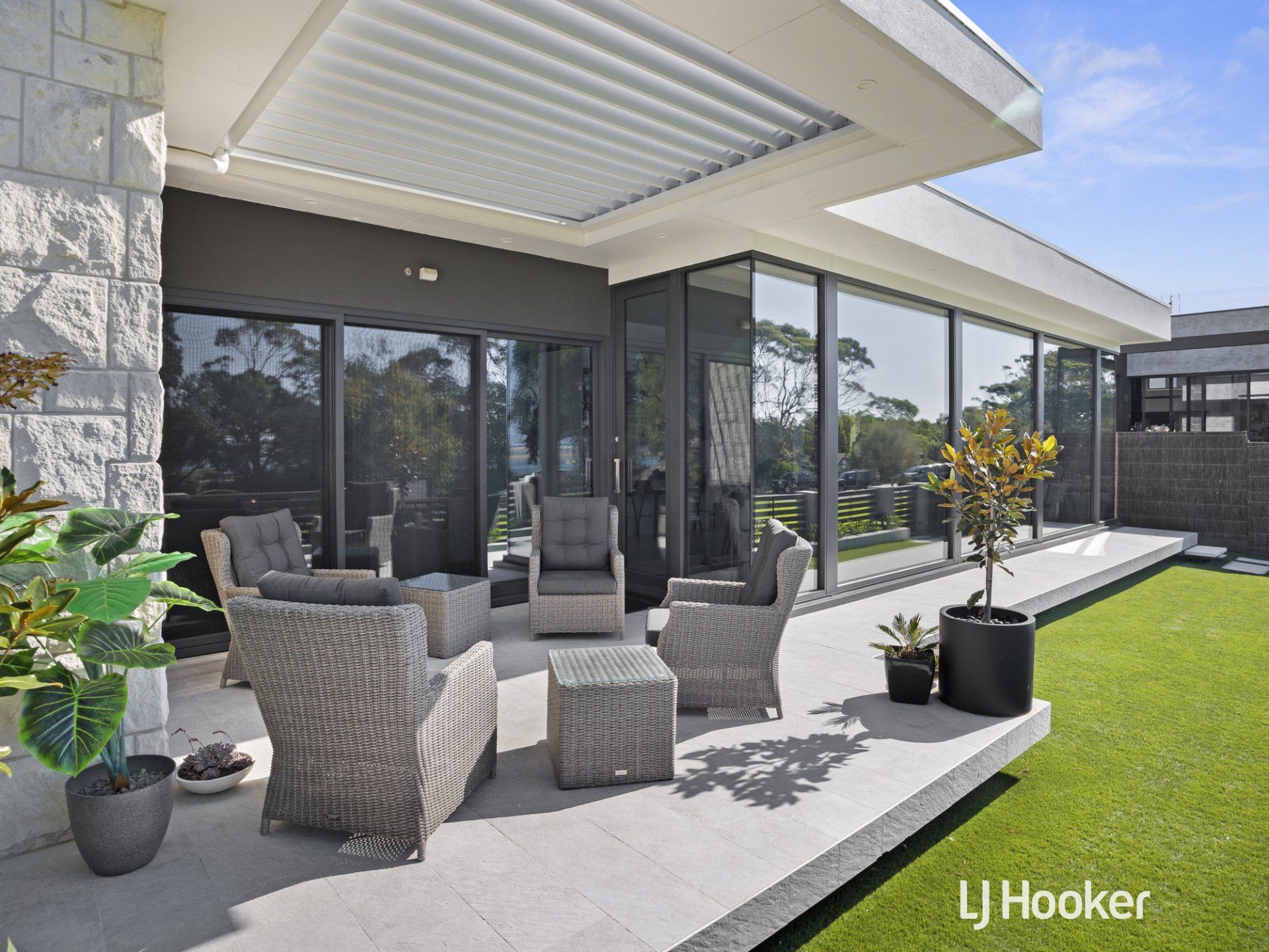 A patio with chairs and a table in front of a house.