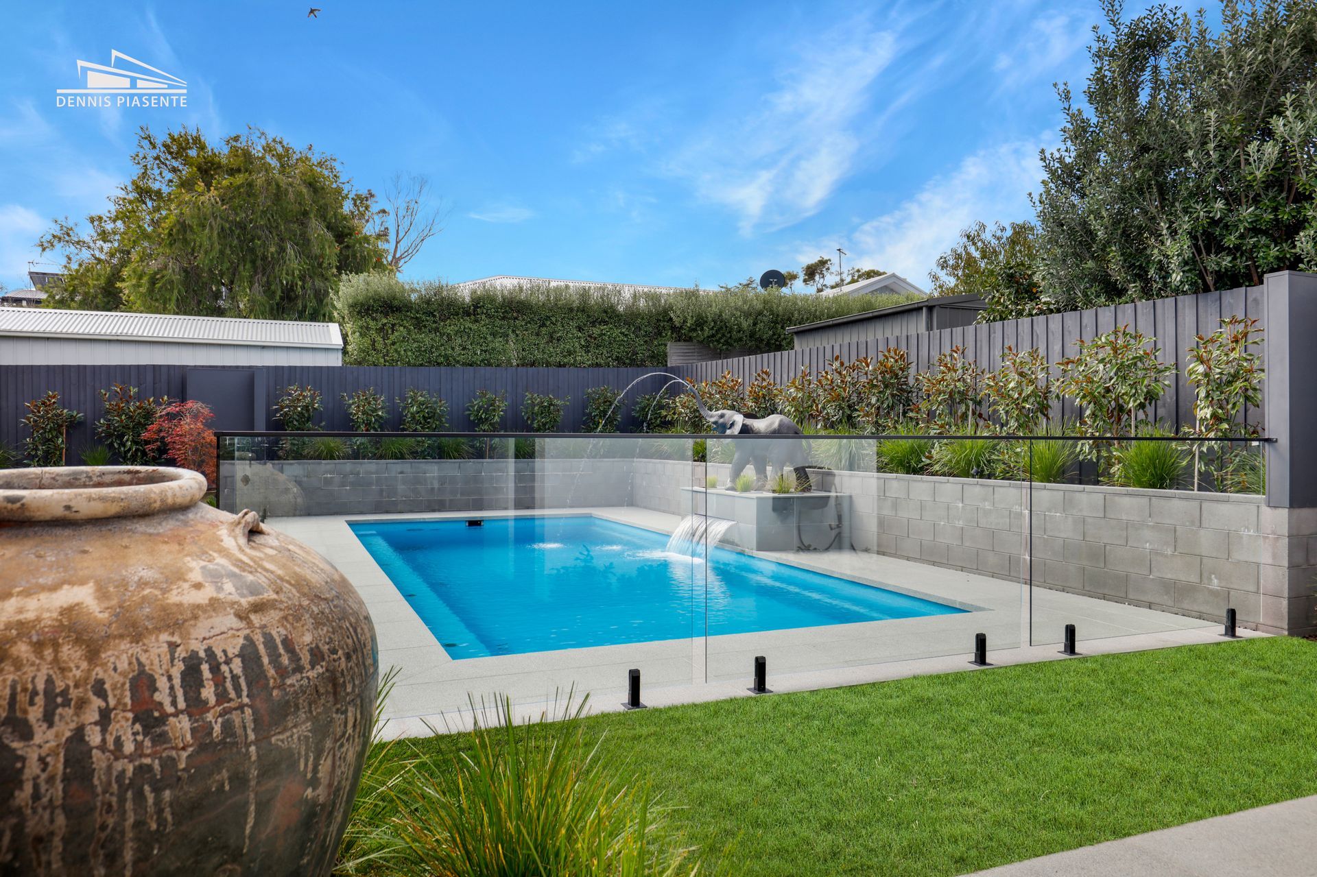 A large swimming pool is surrounded by a glass fence.